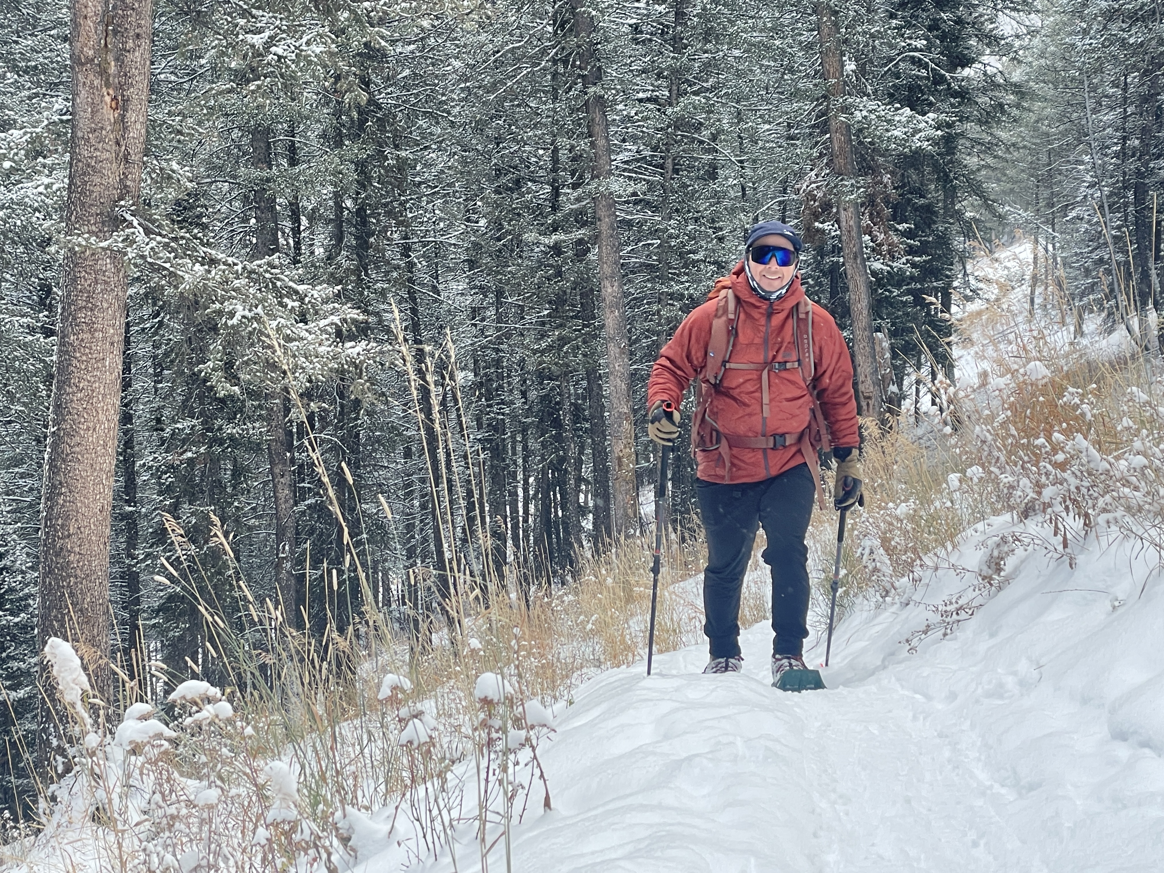 A hiker wearing winter boots while snowshoeing through a snowy forest in the Tetons.