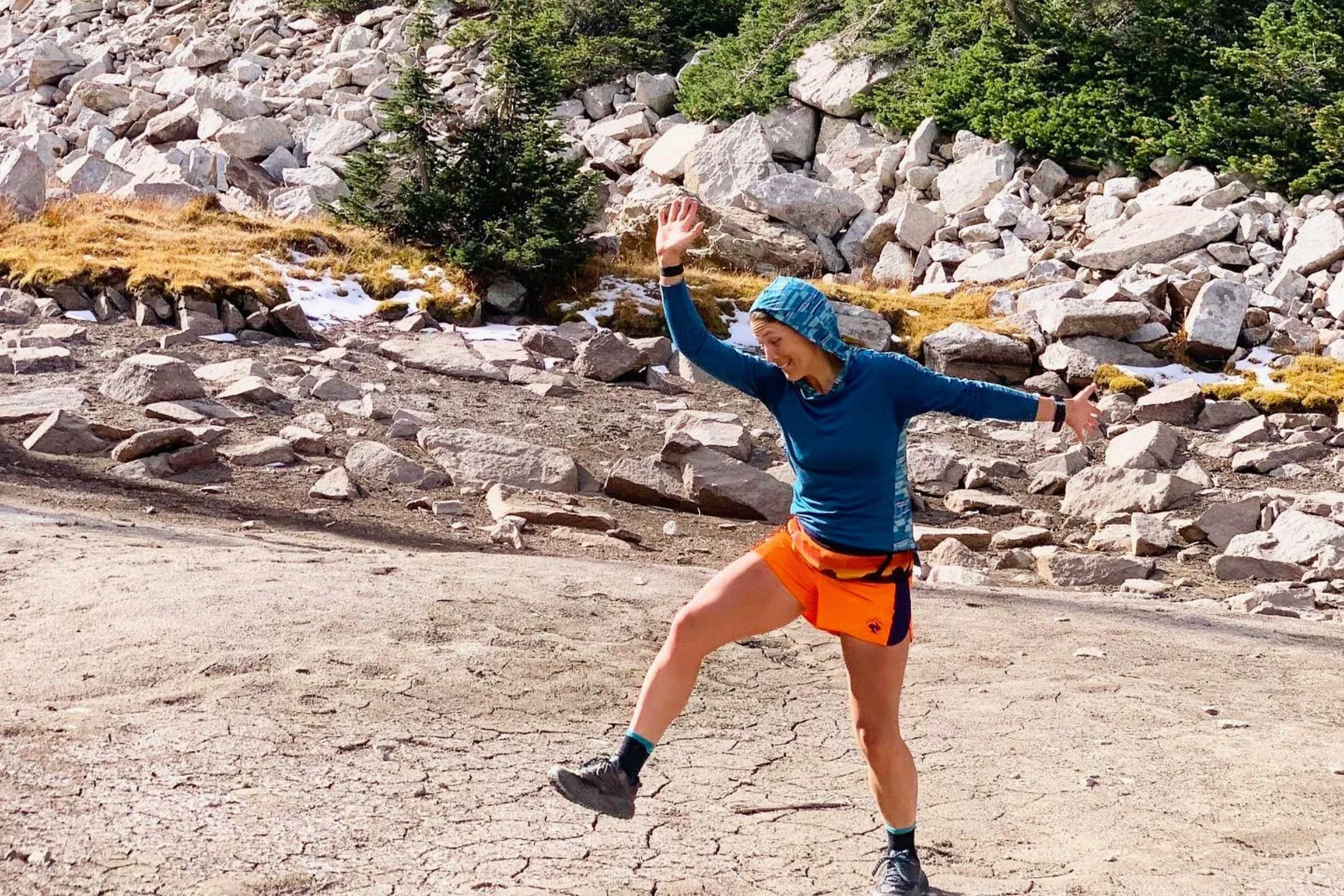 An athlete trail running in a Smartwool base layer hoodie.