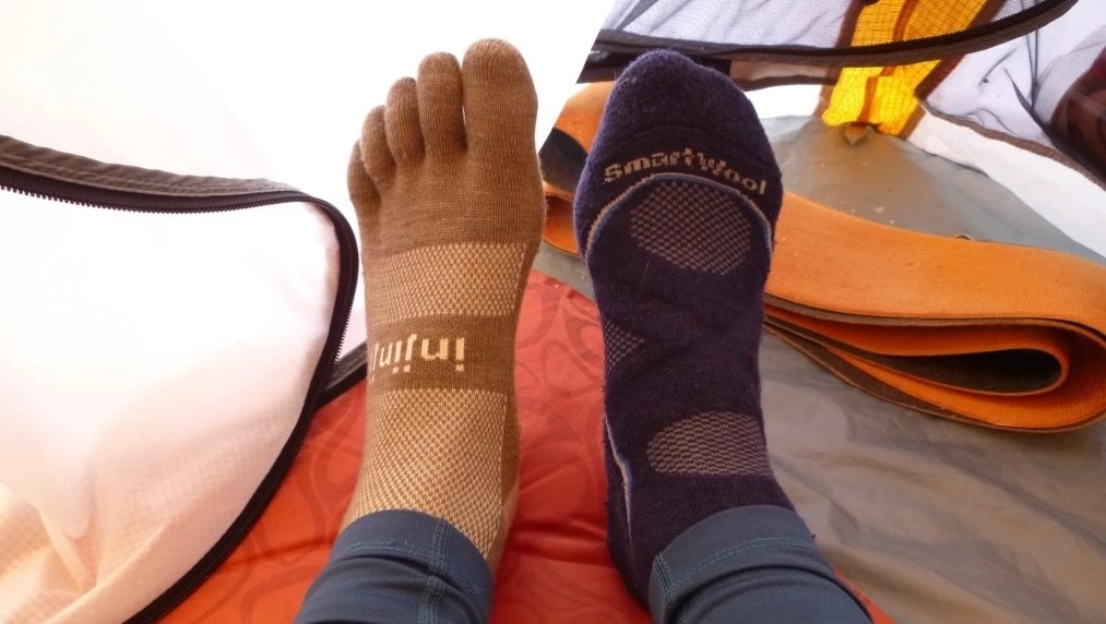 An Injinji toe sock shown next to a traditional Smartwool hiking sock.