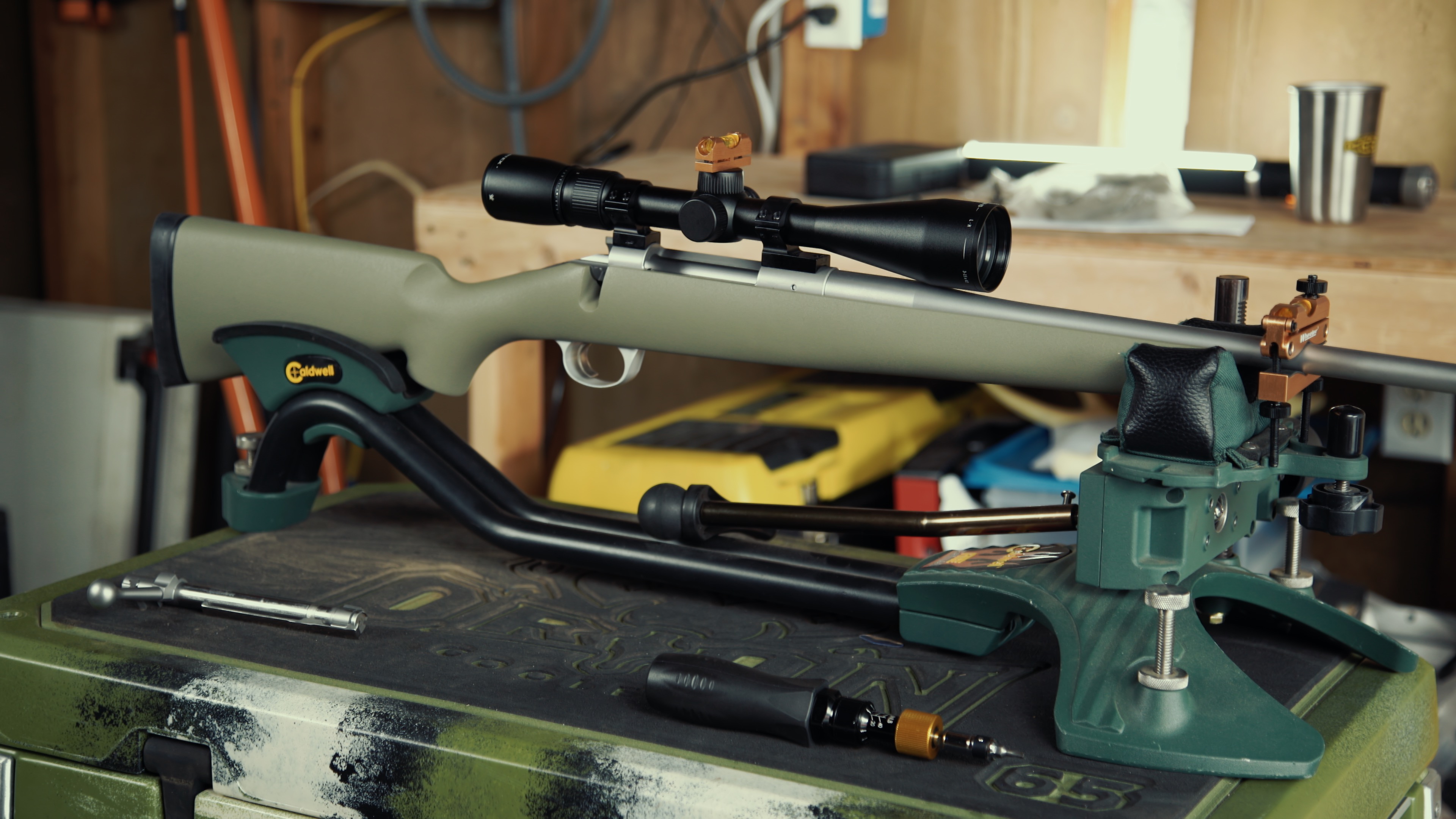 A precision rifle held in a gun vise with spirit levels placed on both the rail and the scope turret to check for alignment.