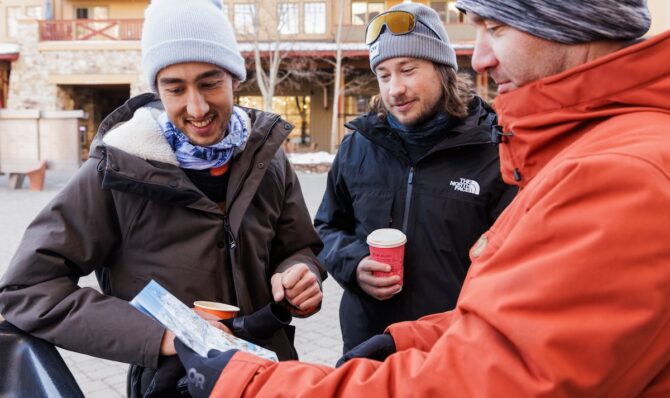 Group of gear testers standing outside a ski lodge with multiple winter jackets.