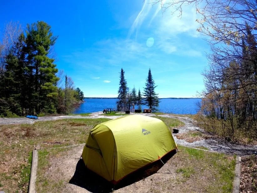 A backcountry campsite in Voyageurs National Park featuring a picnic table and a metal bear-proof food locker.