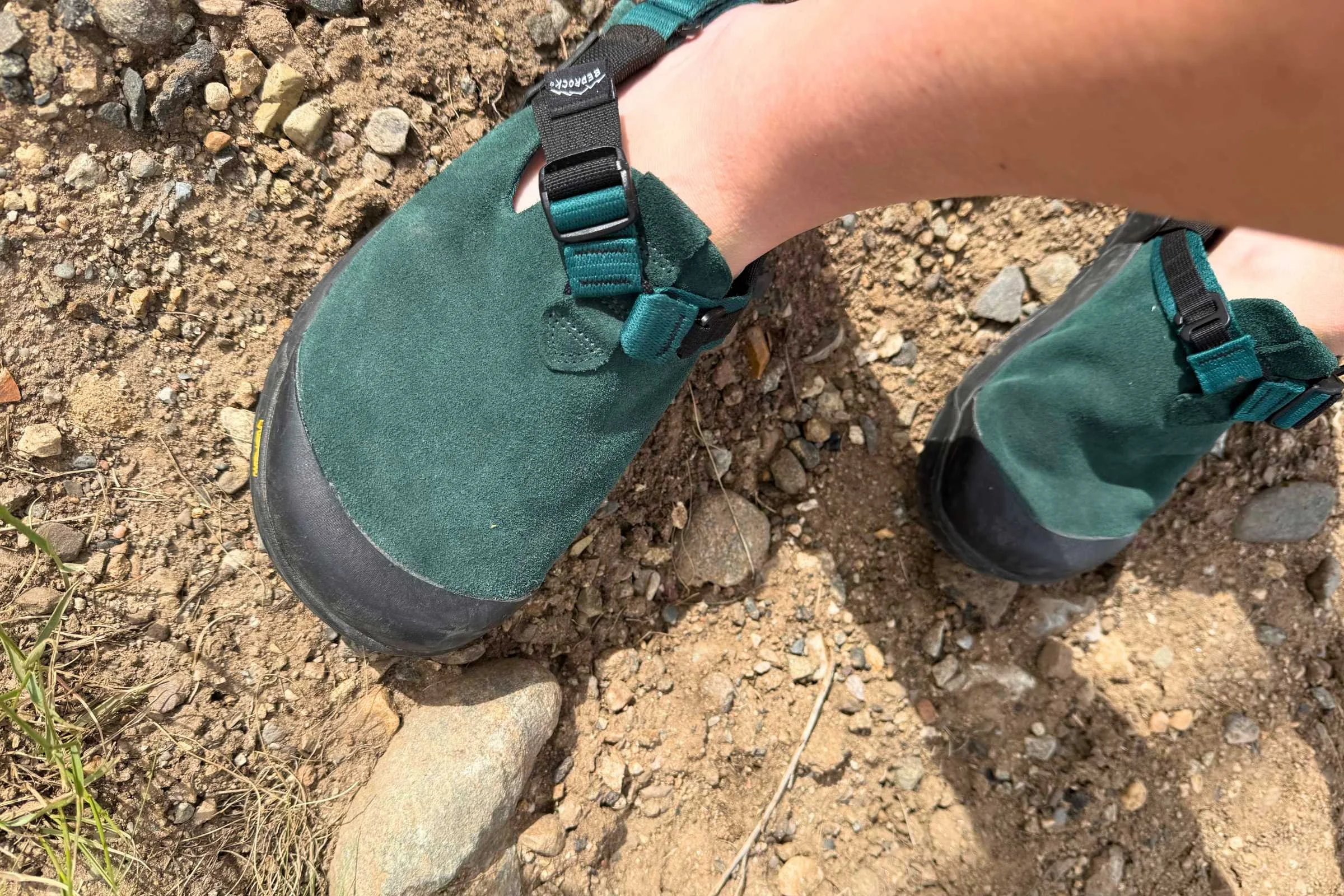 A pair of Bedrock Mountain Clogs worn by a person sitting near a glowing campfire at dusk.