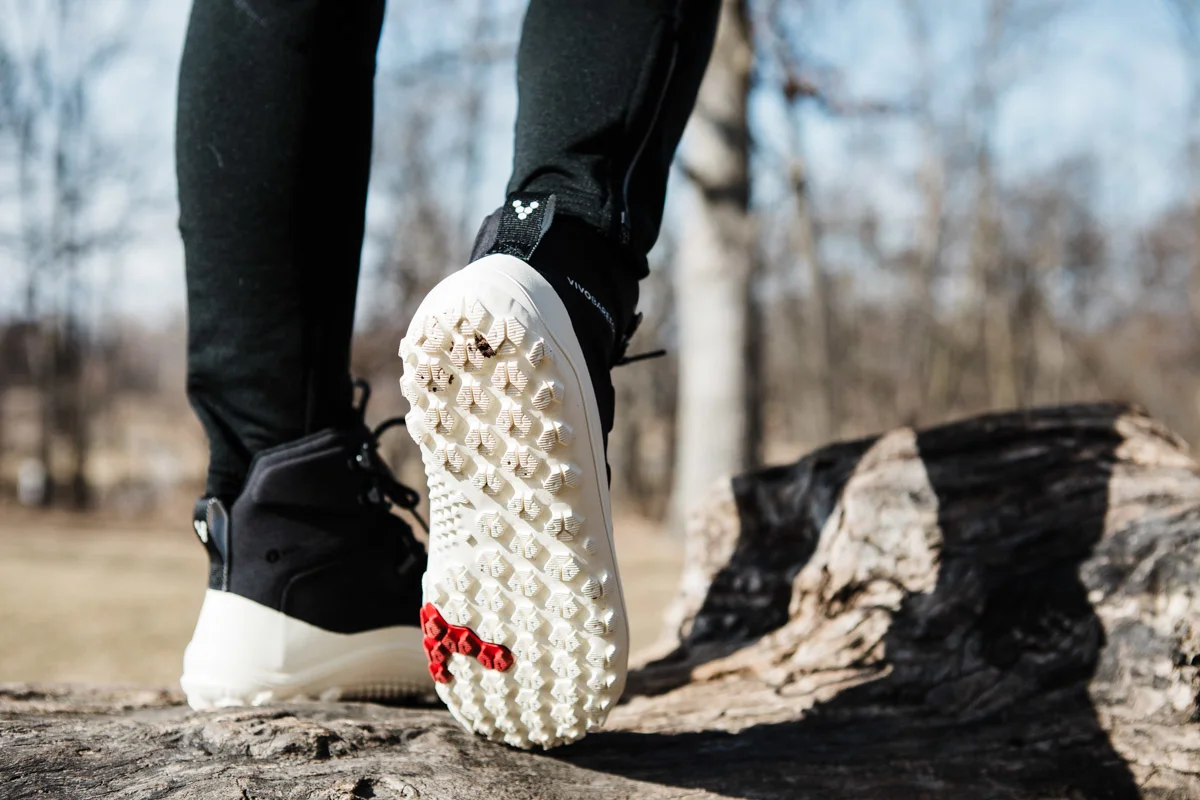 A person wearing Vivobarefoot Tracker boots standing in a natural outdoor setting.
