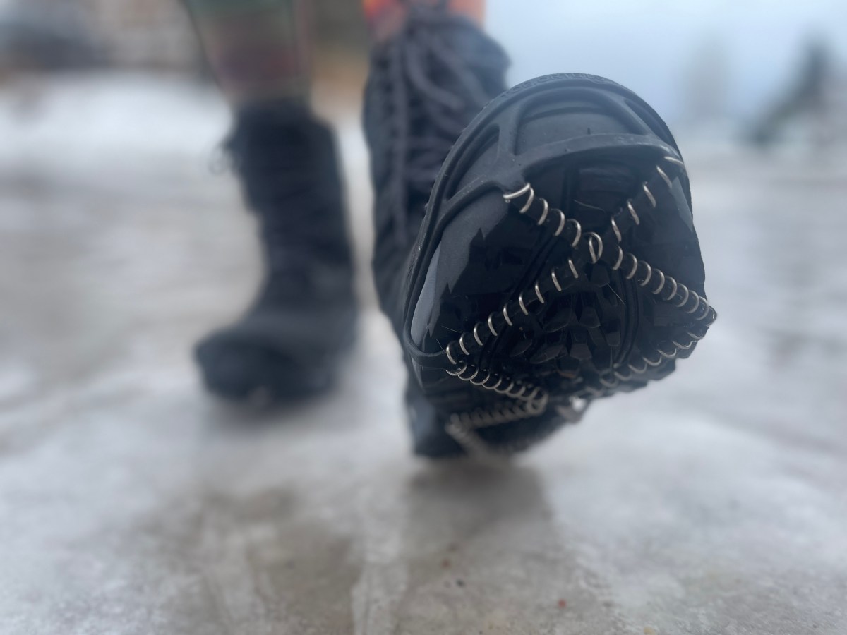 Yaktrax coil-style traction devices fitted on a boot in the snow.