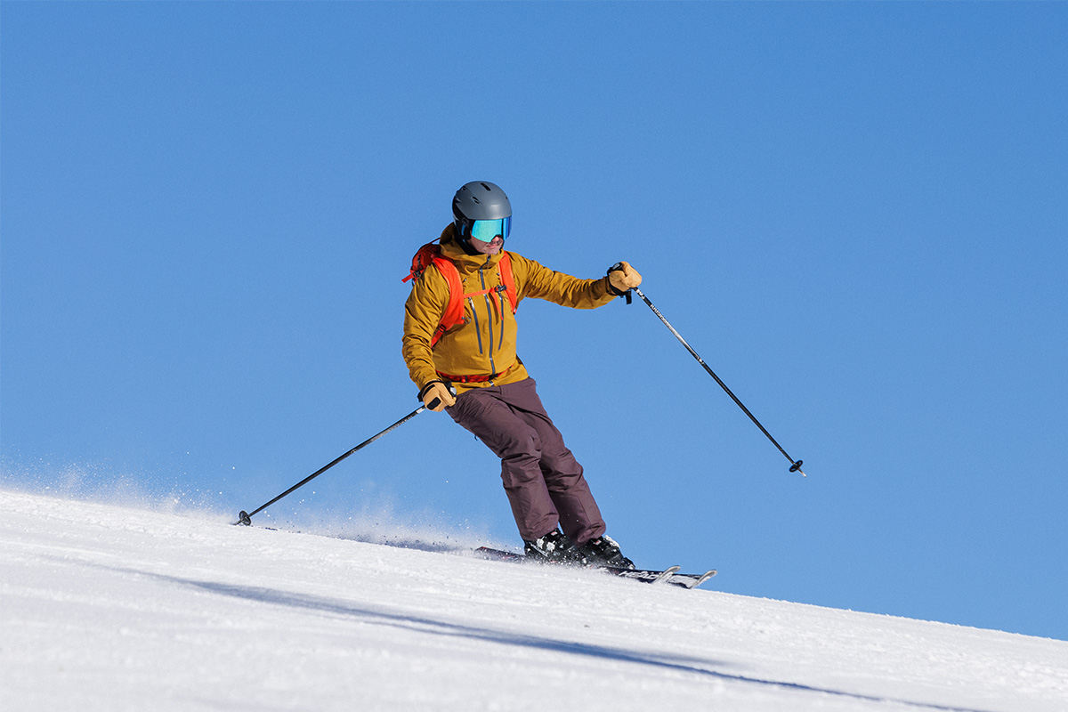 A man skiing in the REI Powderbound pants under a clear blue sky.