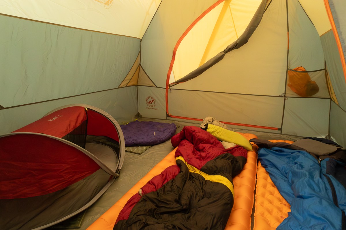 Interior view of the tent showing three sleeping pads and sleeping bags neatly arranged