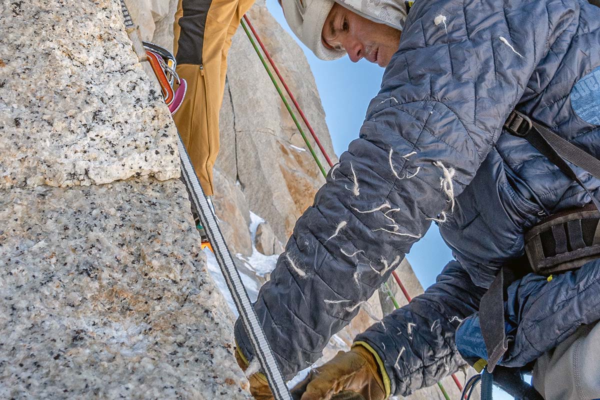 Close-up of a well-worn synthetic jacket with visible abrasions and field repairs.