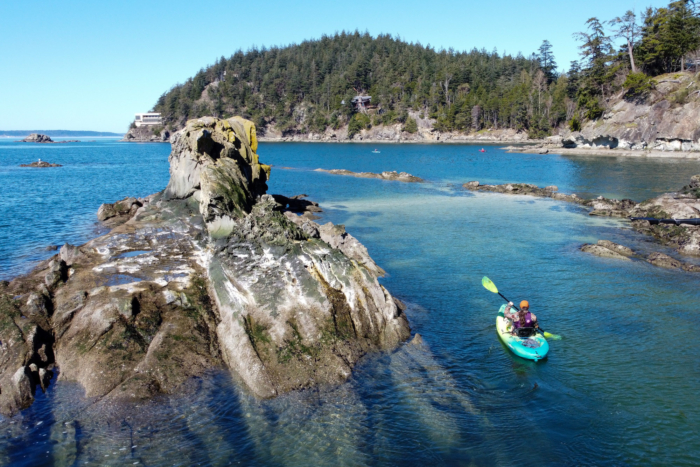 Aerial view of multiple kayakers testing different boats on a lake.