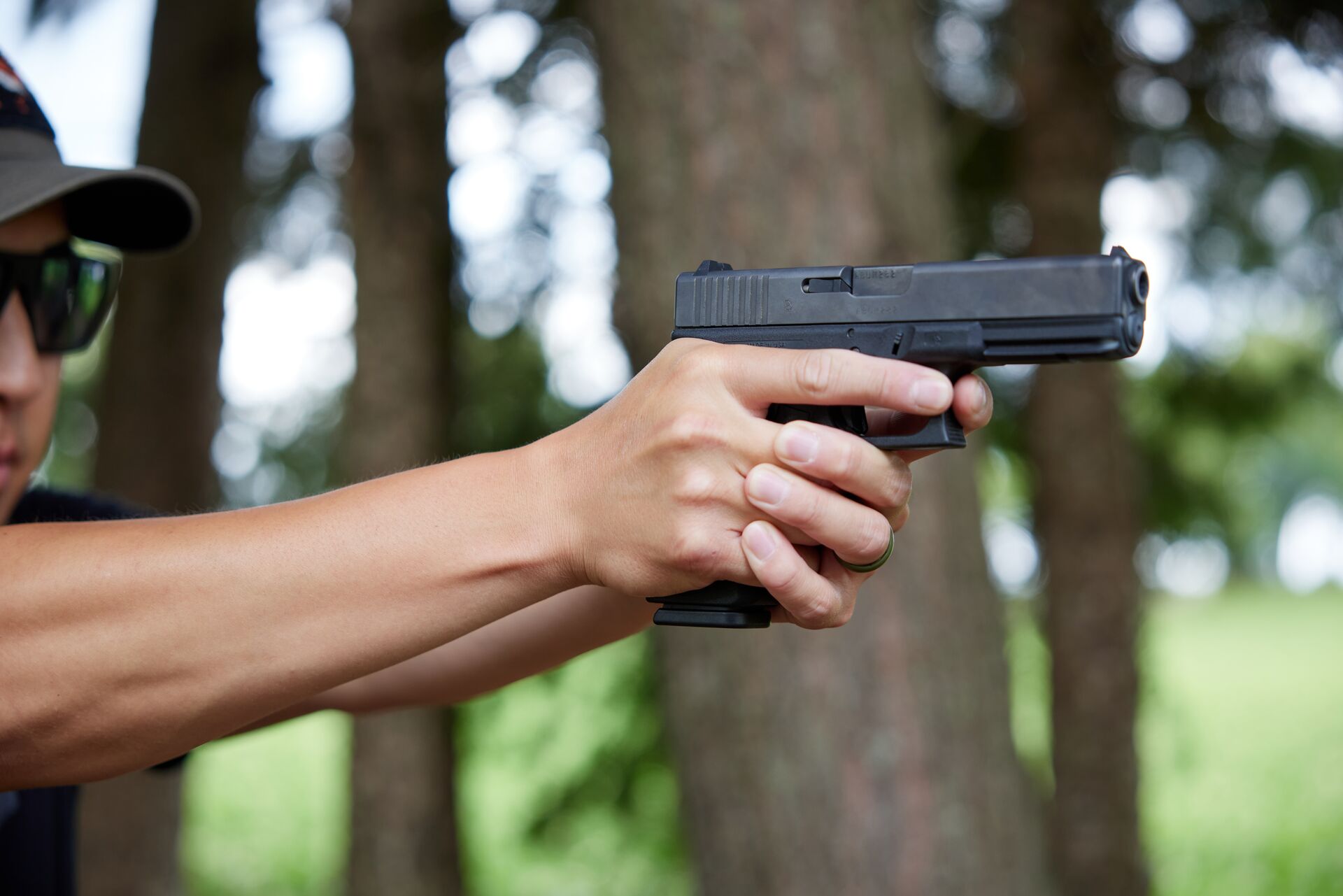 Close-up of a hunter aiming a handgun at a target.