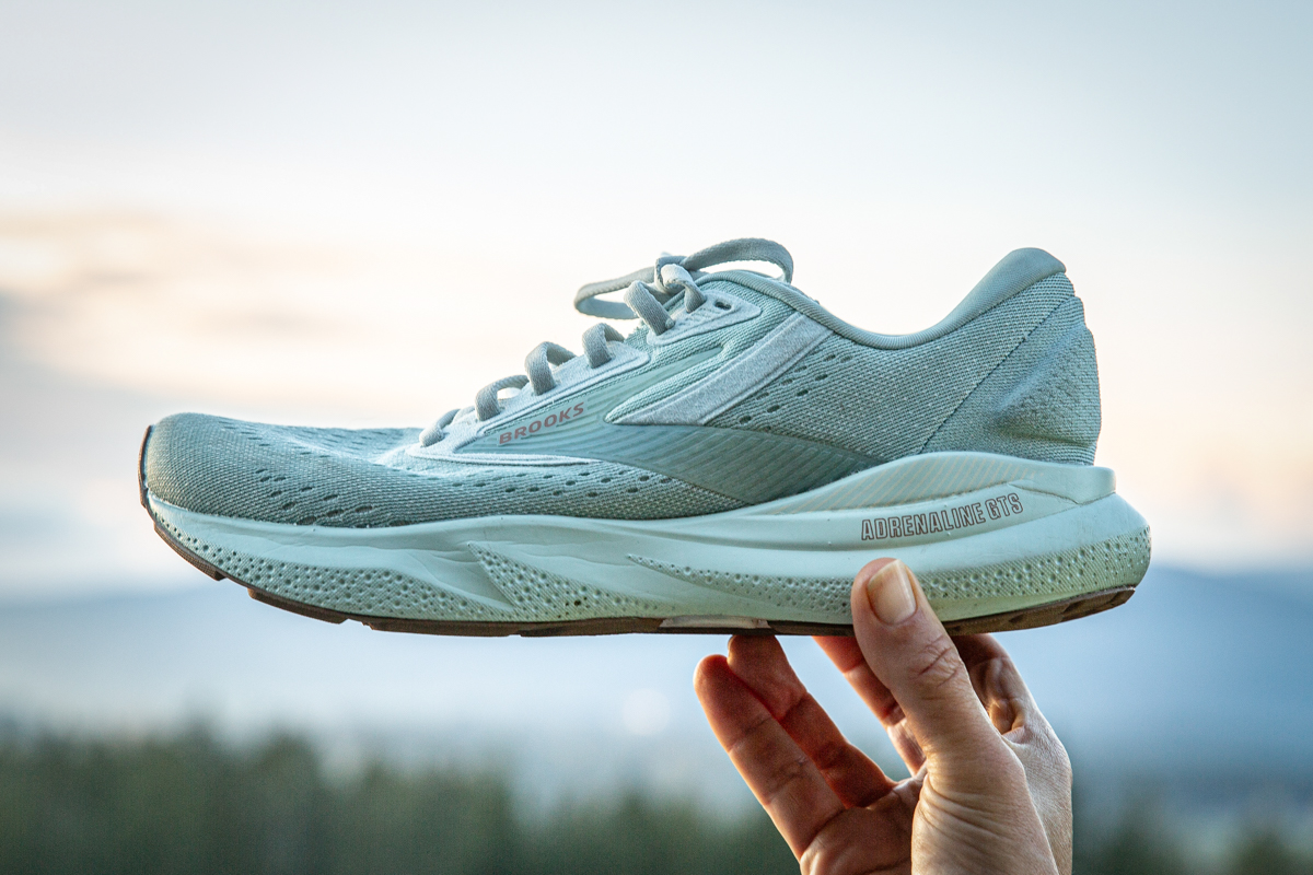 A person holding a Brooks Adrenaline shoe to highlight the thickness of the midsole foam.