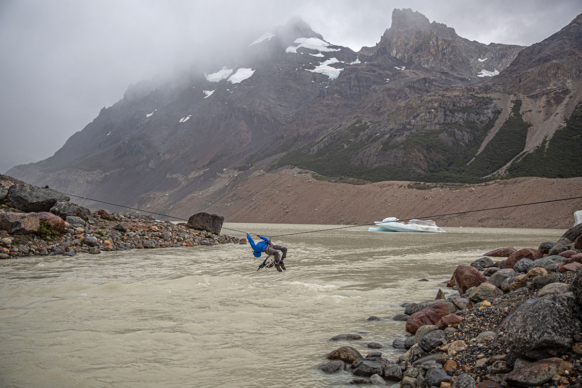 A climber using a rope traverse while wearing a technical hardshell jacket.