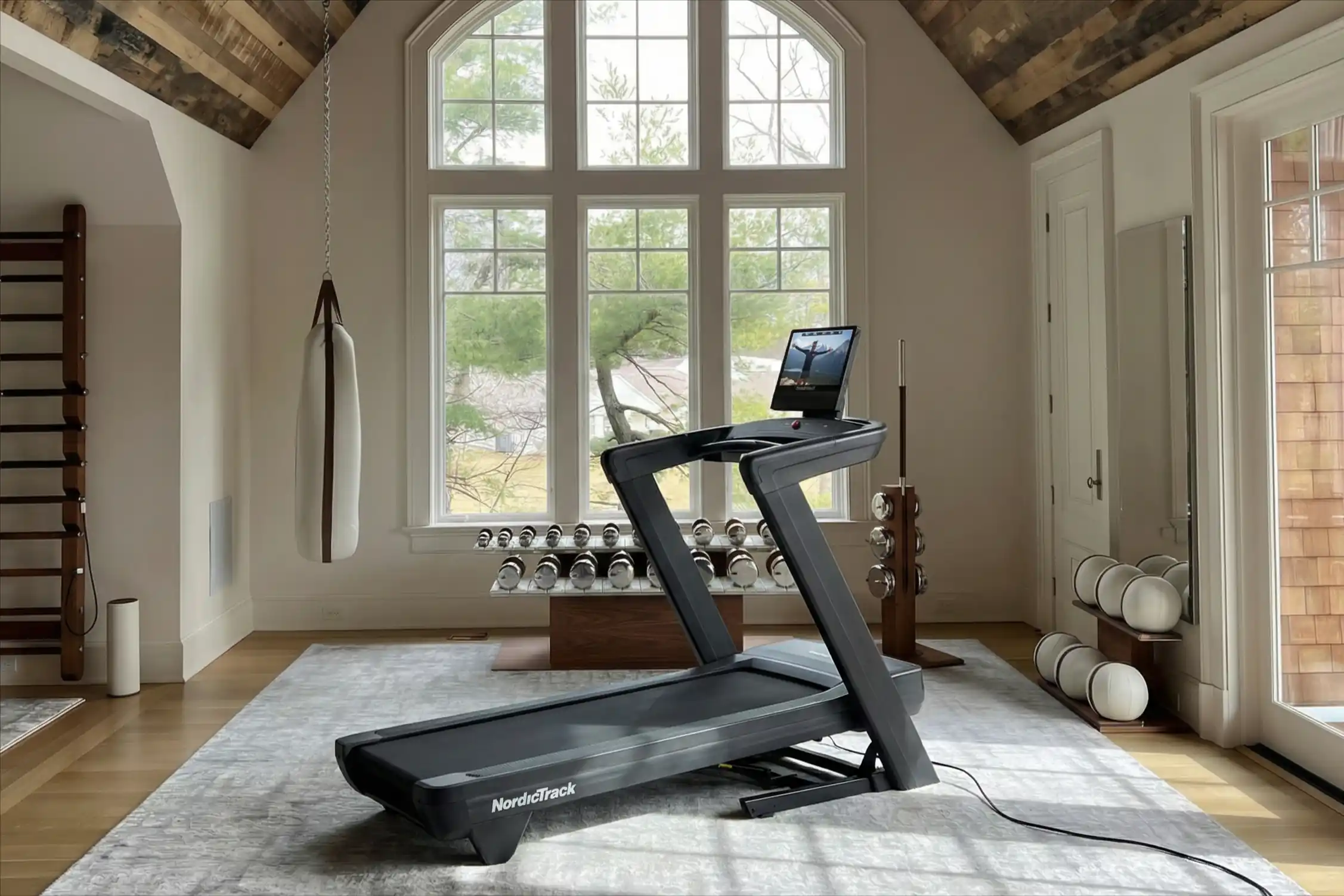 A NordicTrack Commercial 1750 treadmill positioned in an elegant home gym with exposed wooden beams.