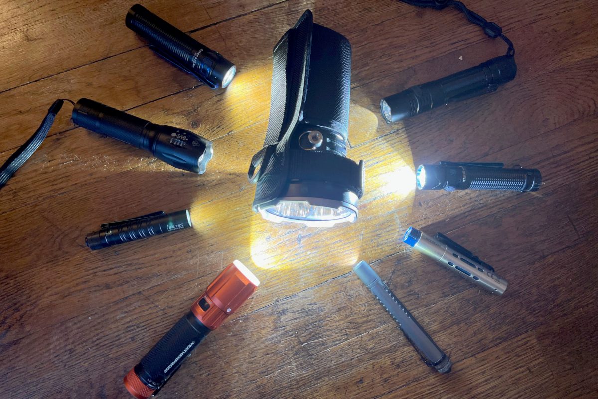 Six different flashlights of varying sizes and tactical designs lined up.