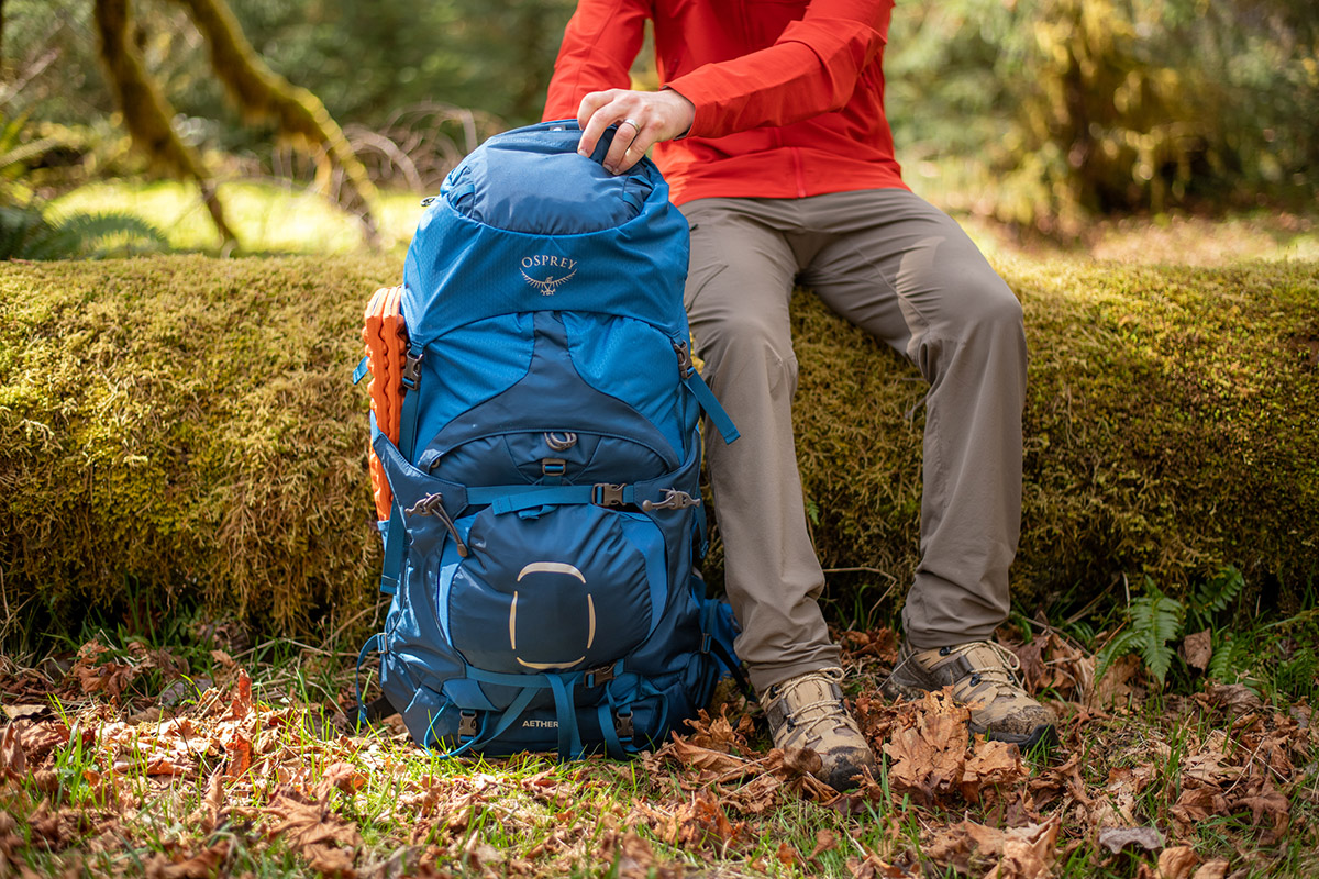 A person sitting on a rocky slope wearing Salomon Quest 4 GTX boots while looking out over a mountain range.