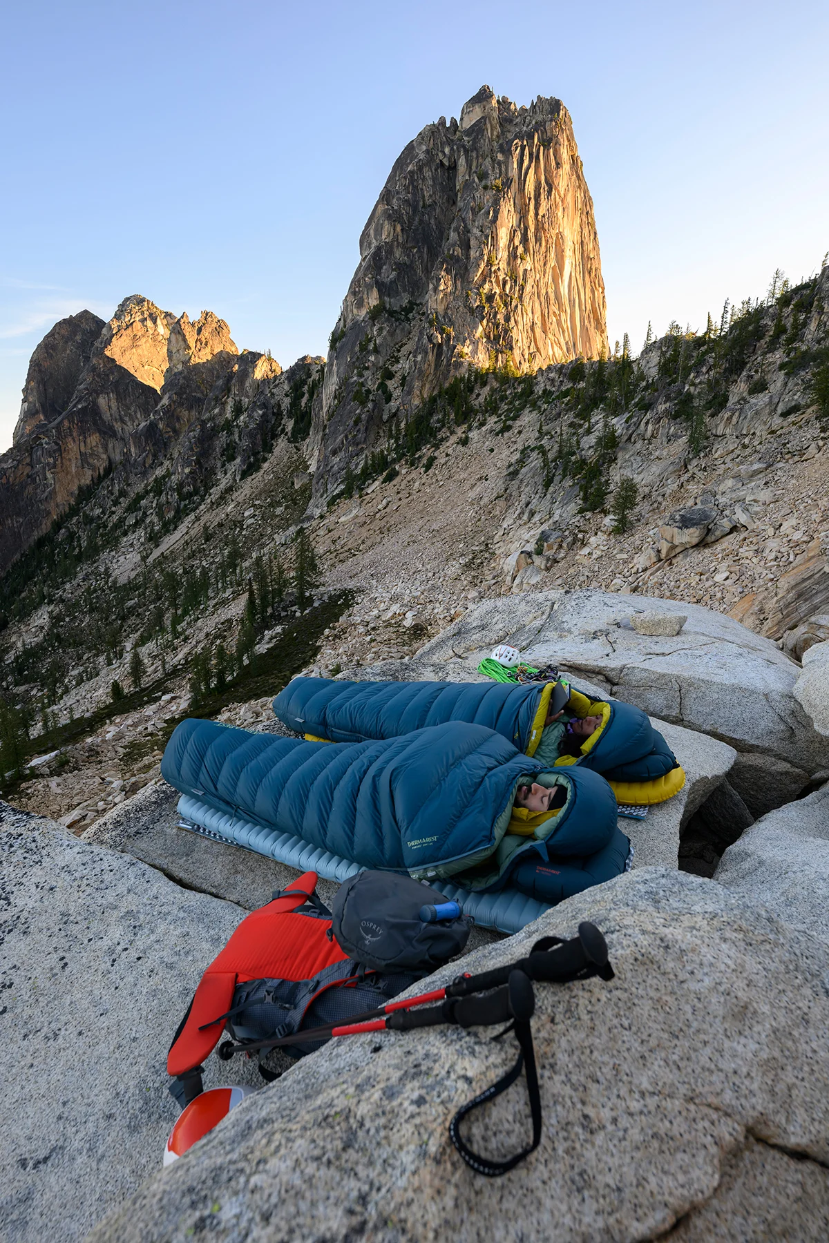 A climber ascending a vertical snow-covered mountain ridge using technical outdoor apparel.