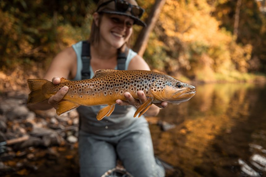 A fisherman holding a trout up briefly for a photo before immediate release.