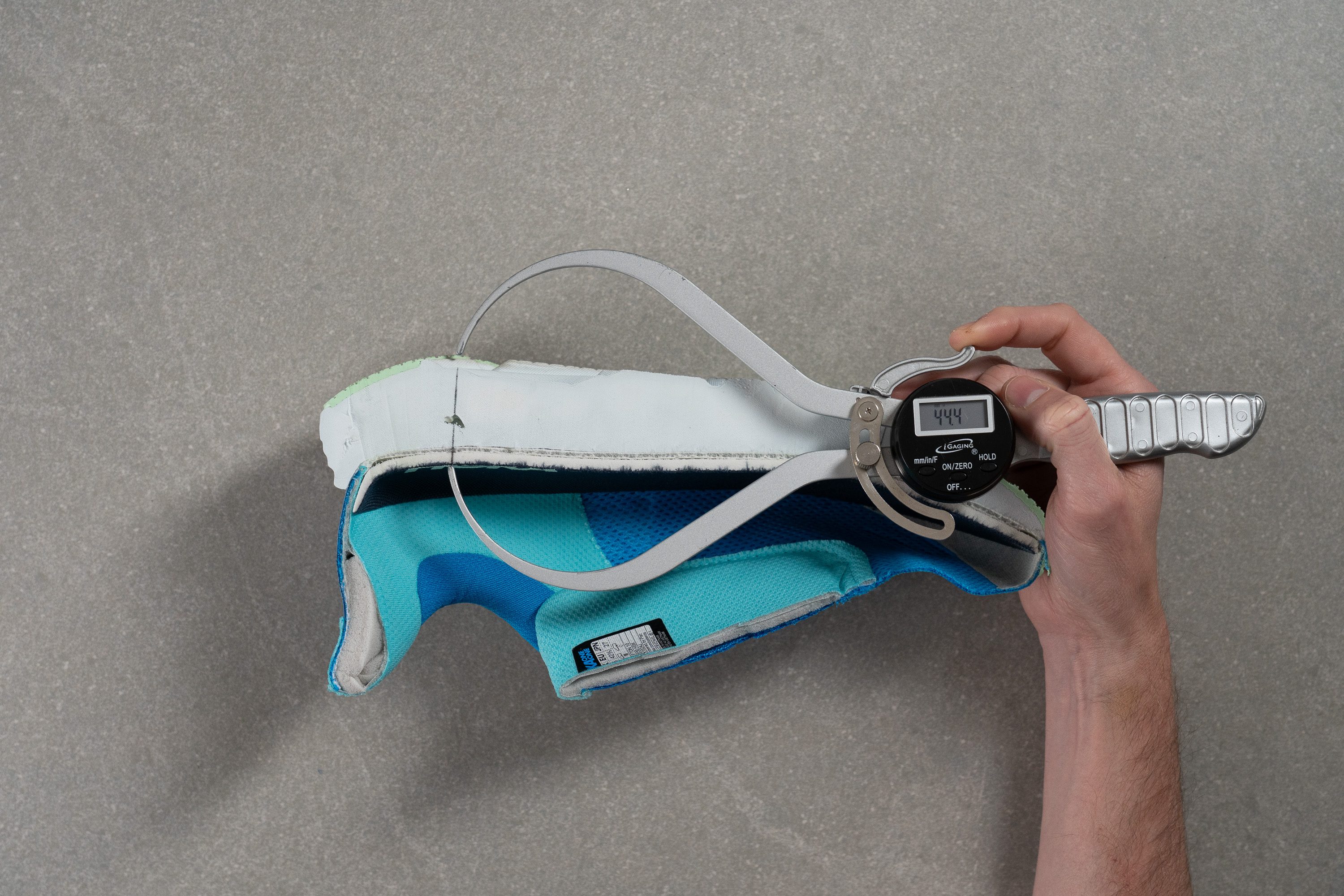 Close-up lab measurement of the Hoka Clifton 10 heel stack height showing 44.4 mm.