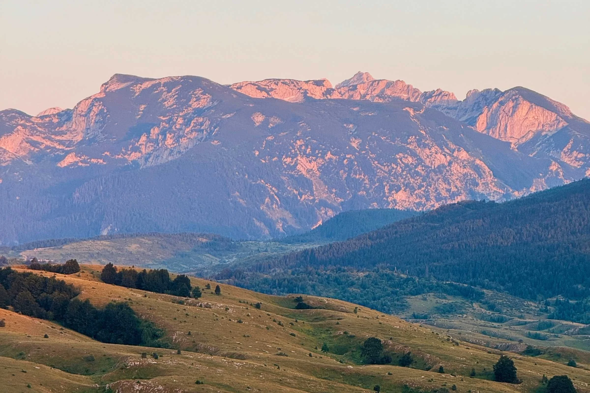 Panoramic view of the Dinaric mountain range with a visible trail winding through the hills.