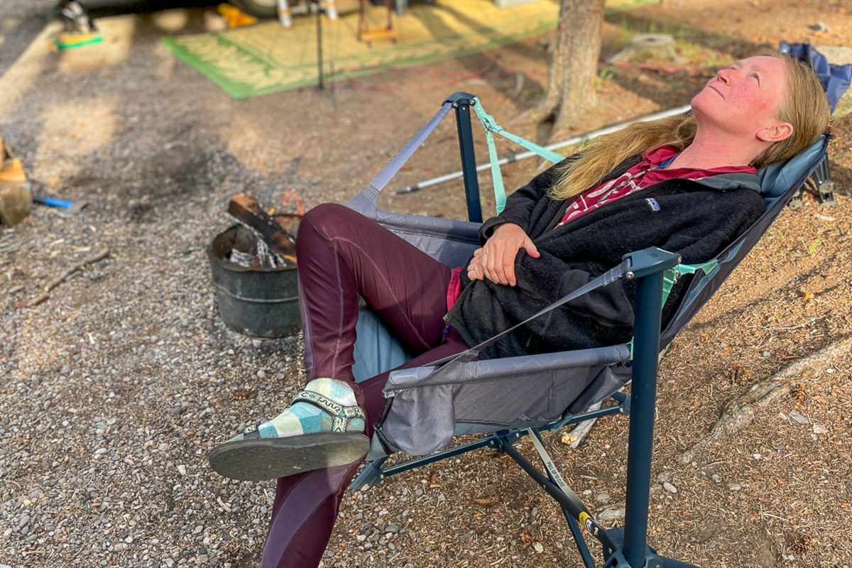 A person reclining deeply in a NEMO Stargaze EVO-X at a campsite at dusk.