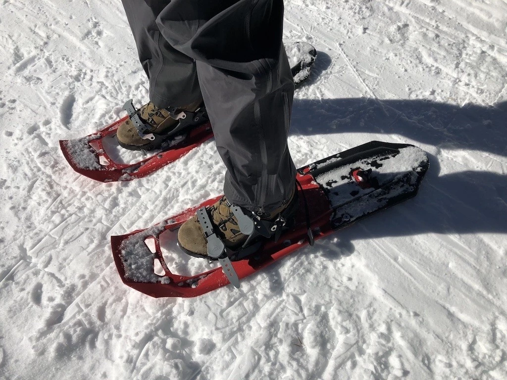 Close-up of a person attaching a flotation tail to the back of a plastic snowshoe.