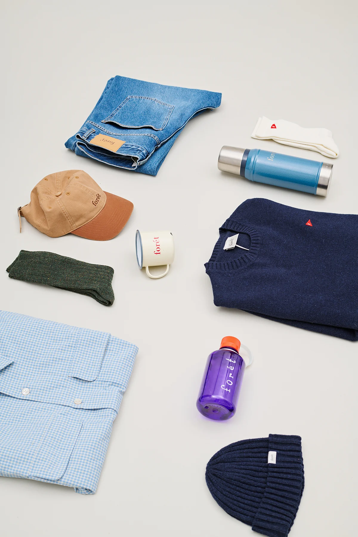 An assortment of Forét apparel including shirts, jackets, and accessories displayed together.