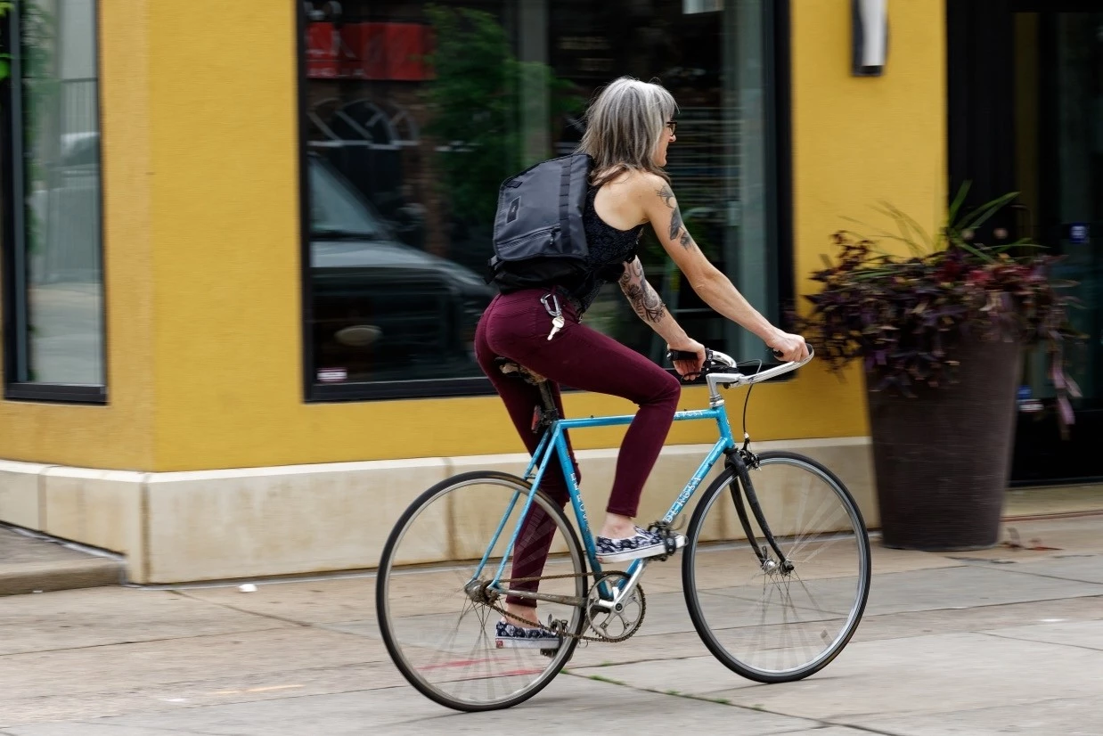 A cyclist wearing the Timbuk2 Especial Stash messenger bag which sits vertically on their back.