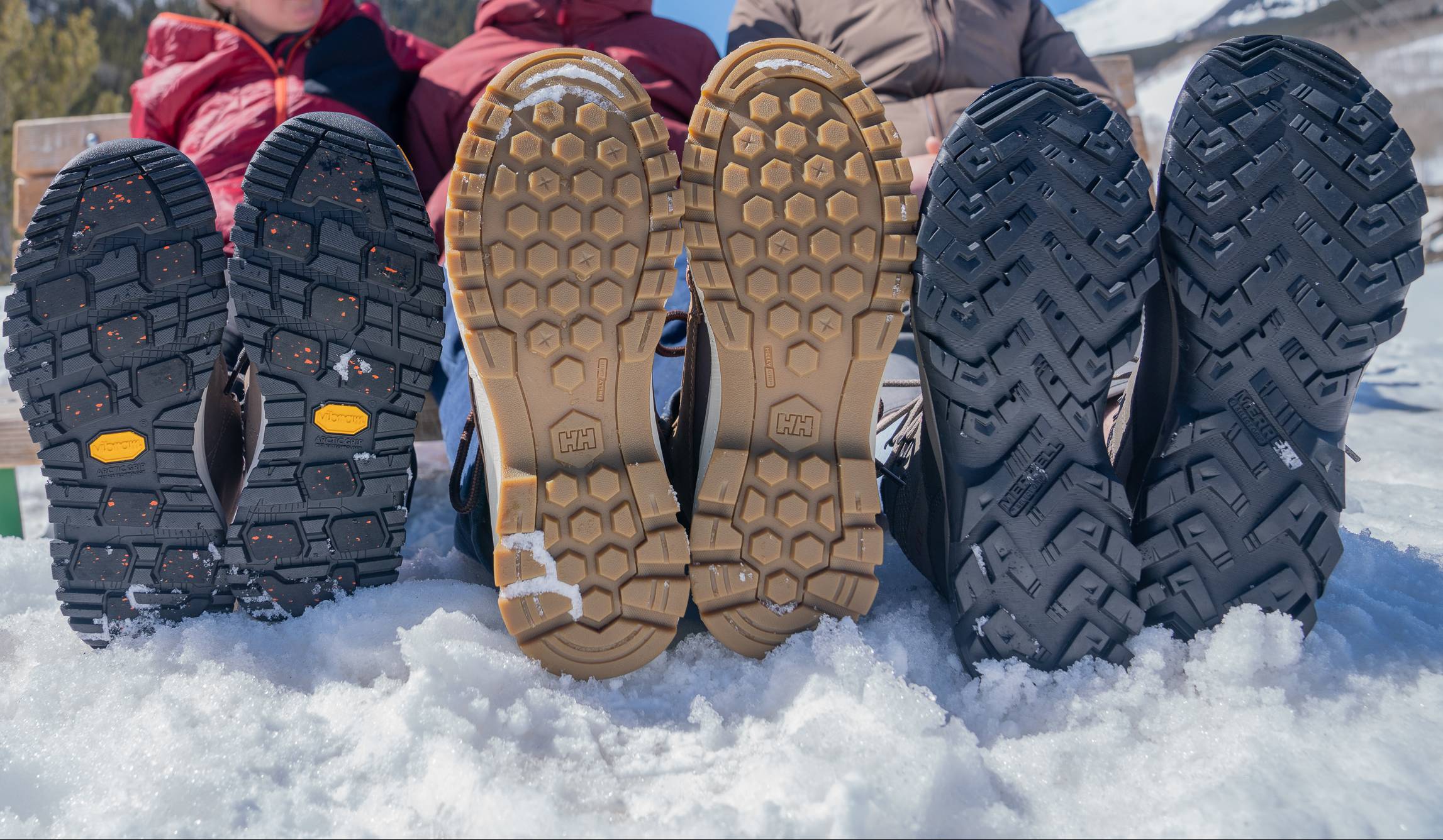 A rows of different winter boot outsoles showing various tread patterns and rubber compounds.