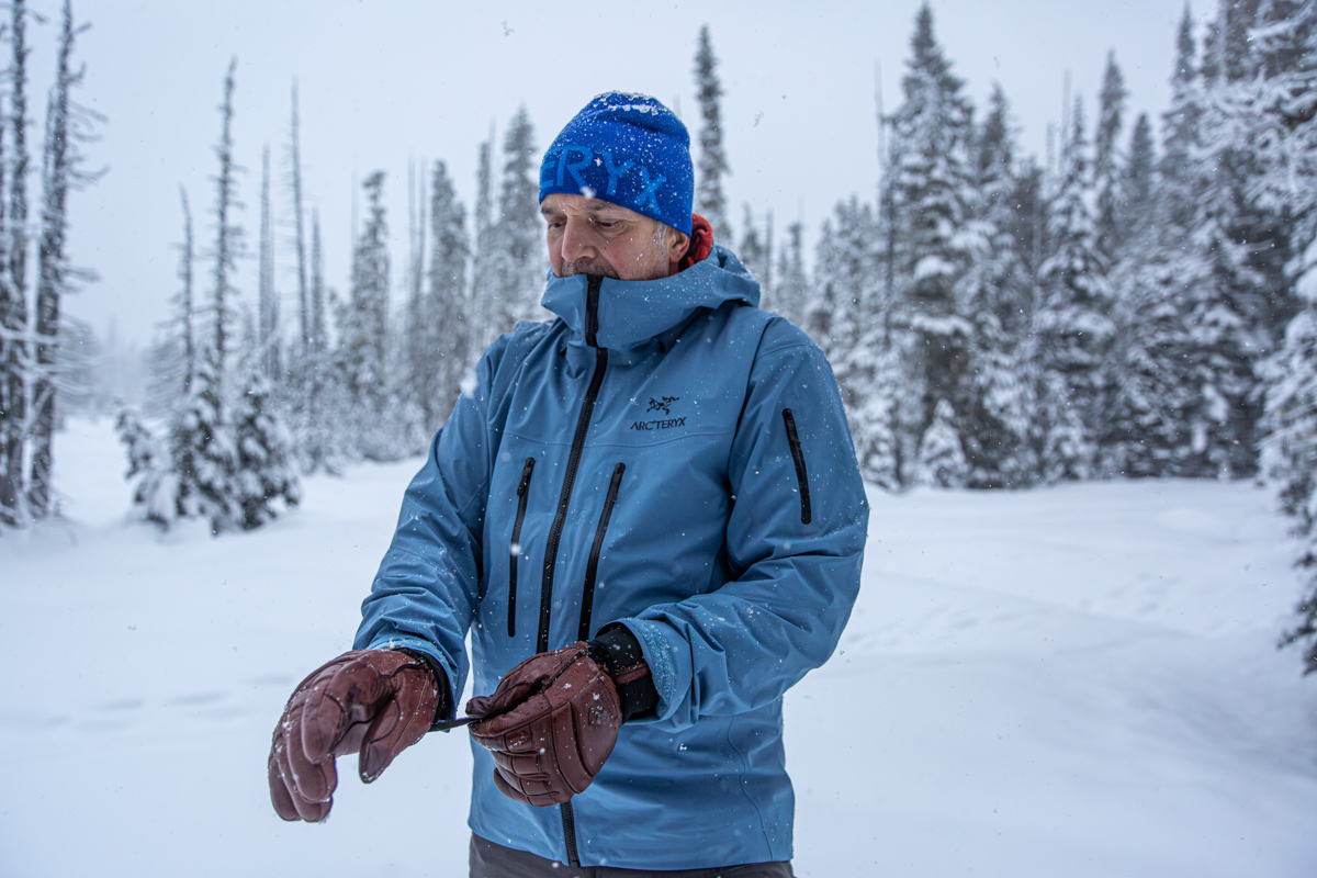 A man wearing a red Arc'teryx Alpha SV jacket in a heavy snowstorm.