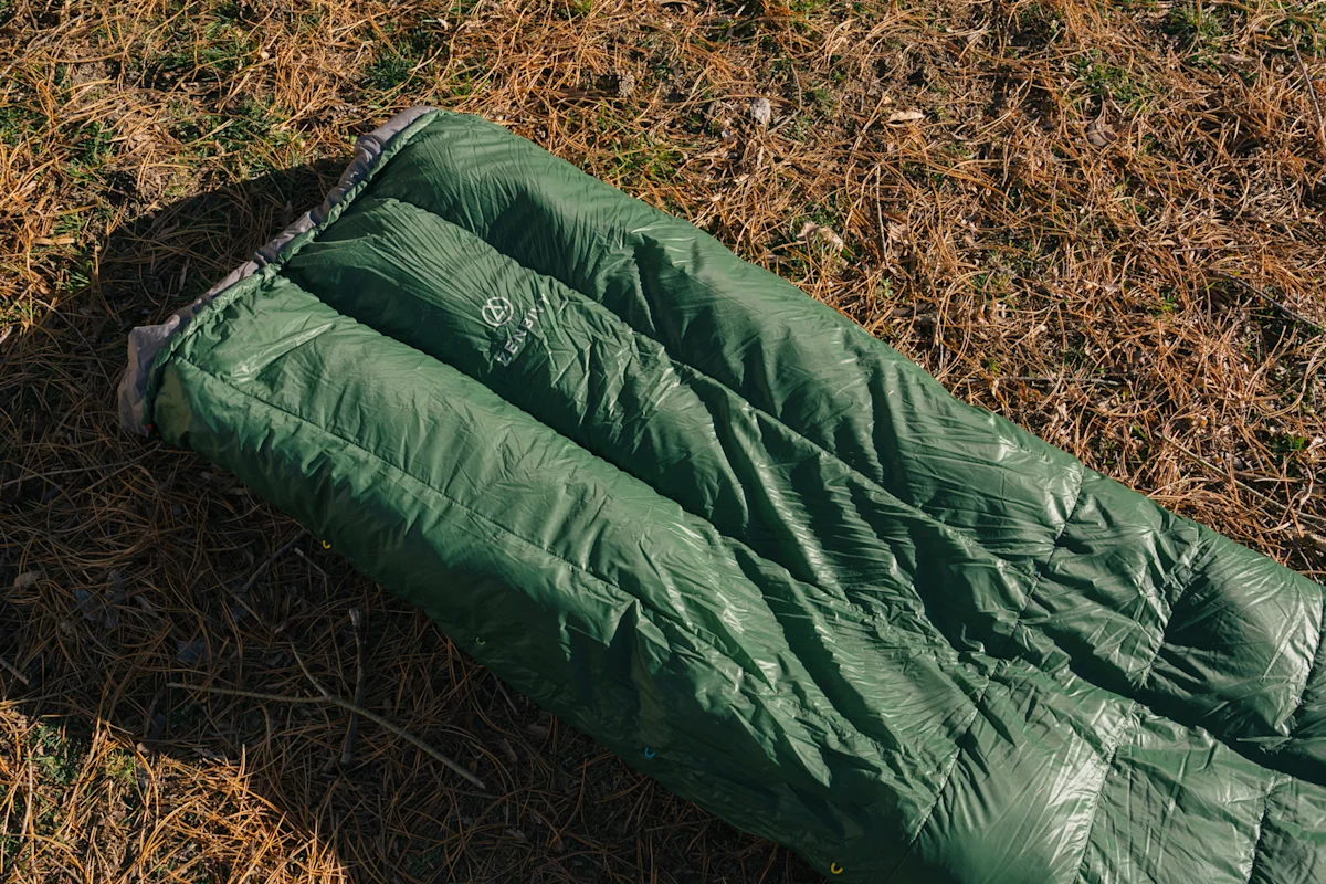 An ultralight quilt securely attached to a sleeping pad with a strap system.