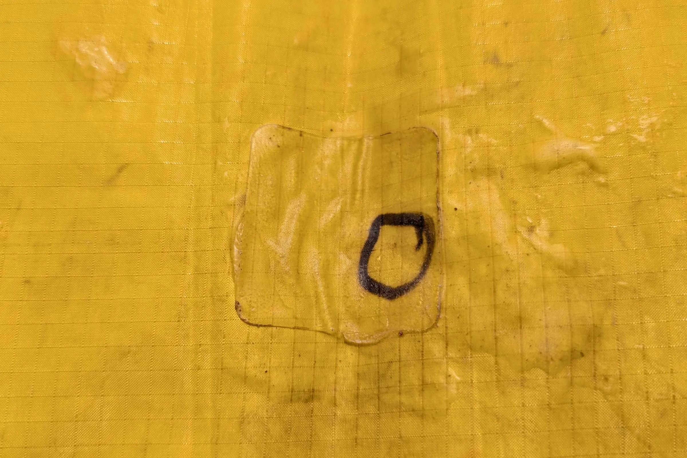 A close-up of a hand using a permanent marker to circle a hole on an orange sleeping pad.