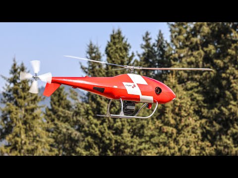 A Swiss Alpine Rescue drone hovering near a steep, rocky mountain face.