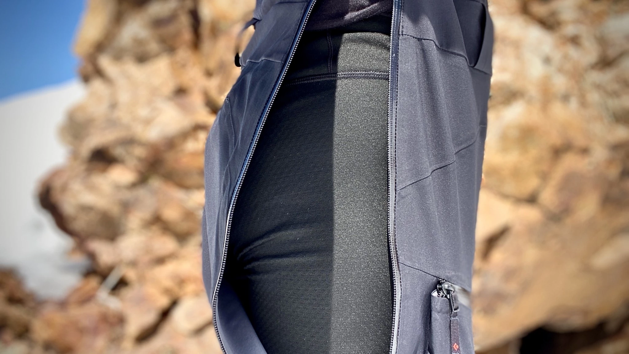 A woman wearing high-waisted synthetic base layer bottoms being prepared for layering under ski gear.