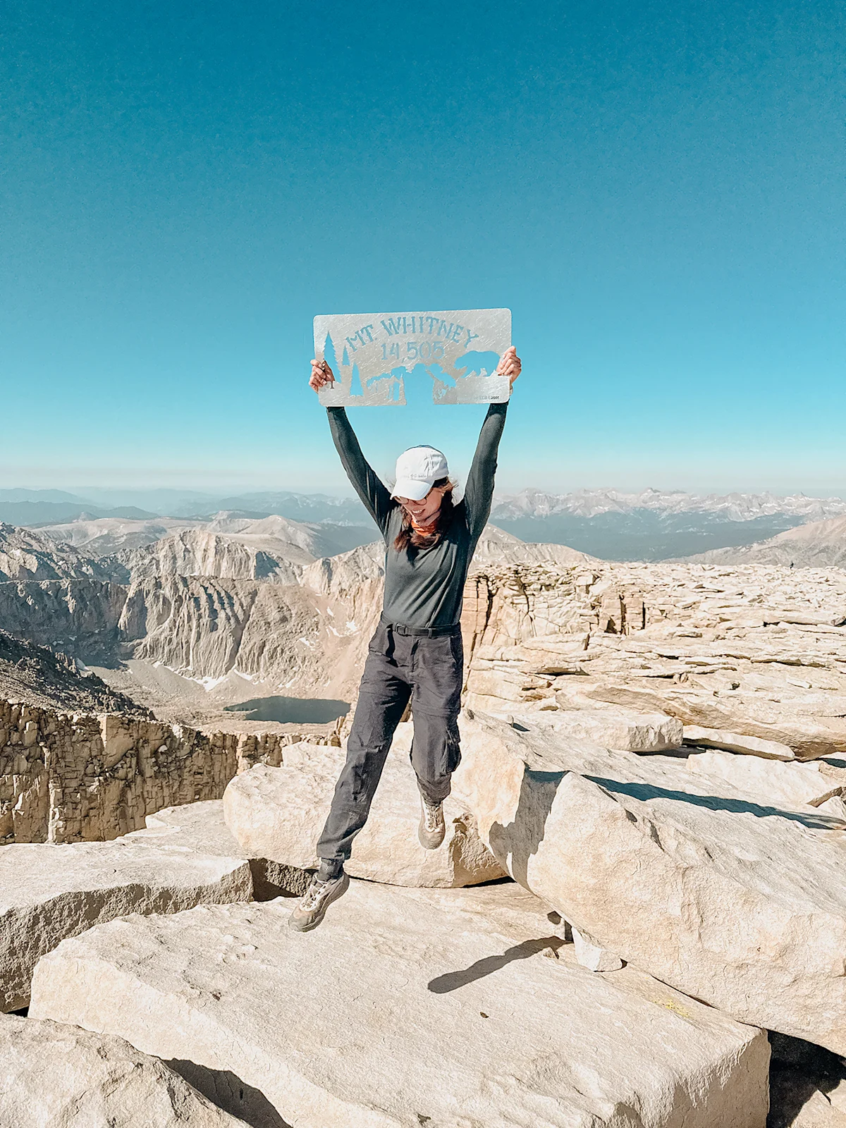 A hiker at the Mount Whitney summit wearing Salomon Genesis shoes