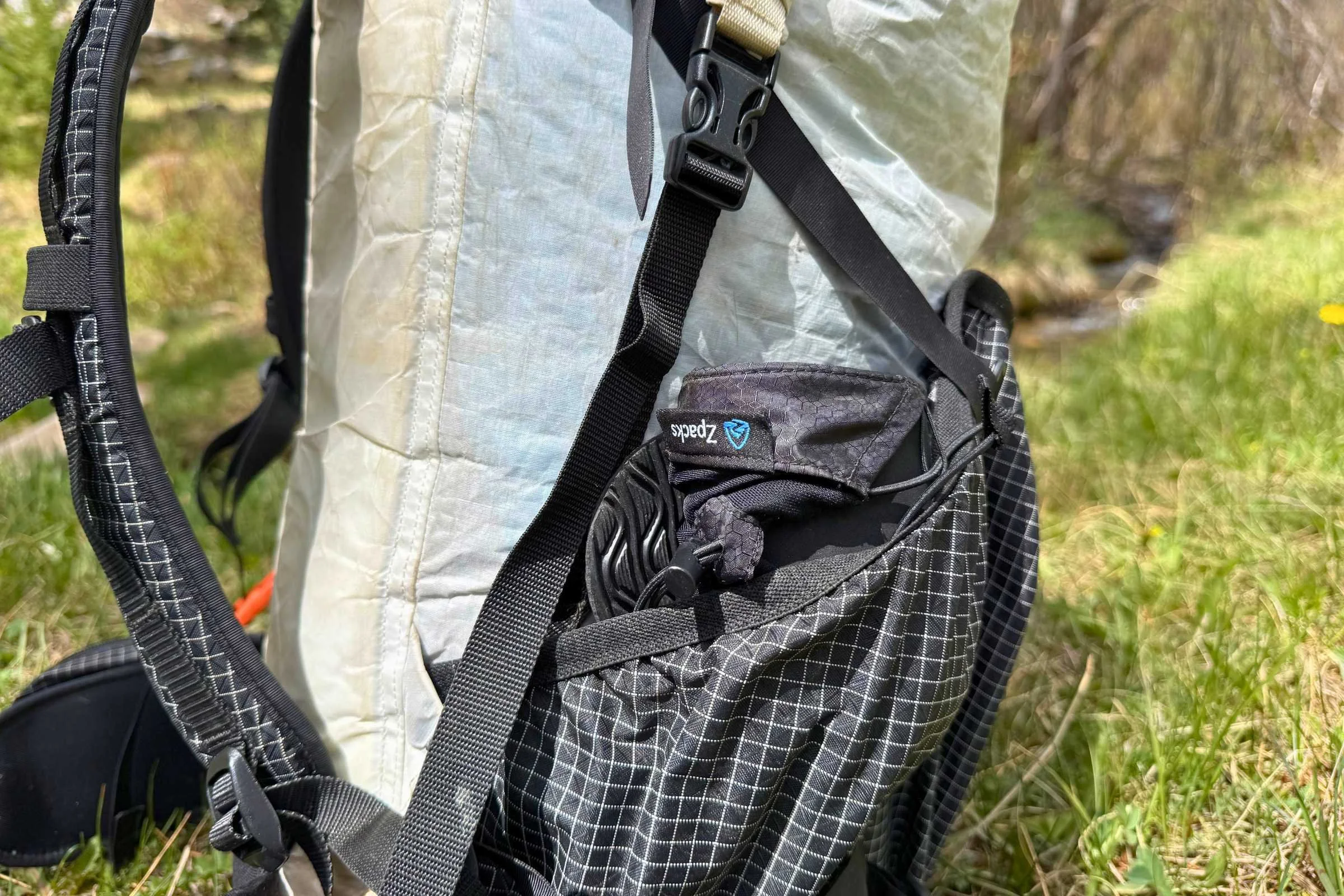A pair of ultralight camp shoes compressed and stored inside a black mesh gear bag.