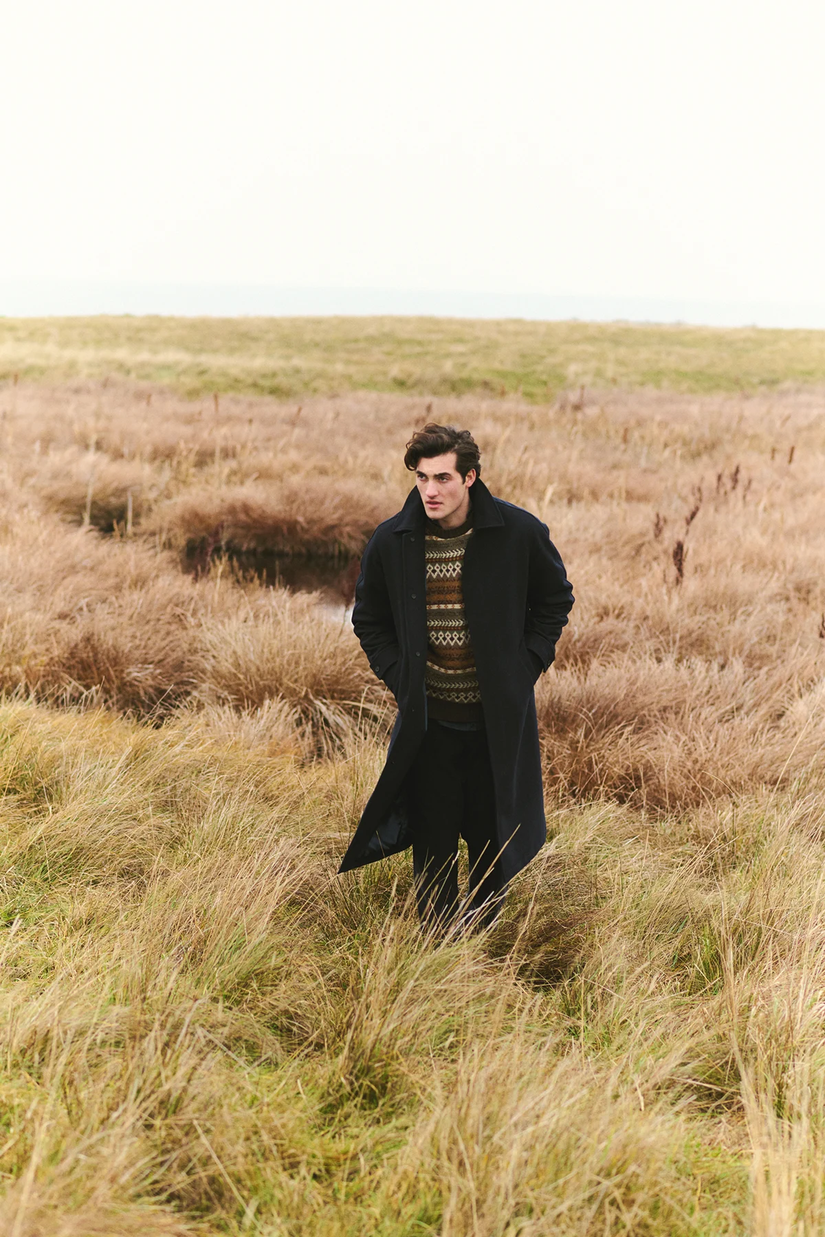 A person walking through a misty, wooded landscape wearing Forét outdoor apparel.