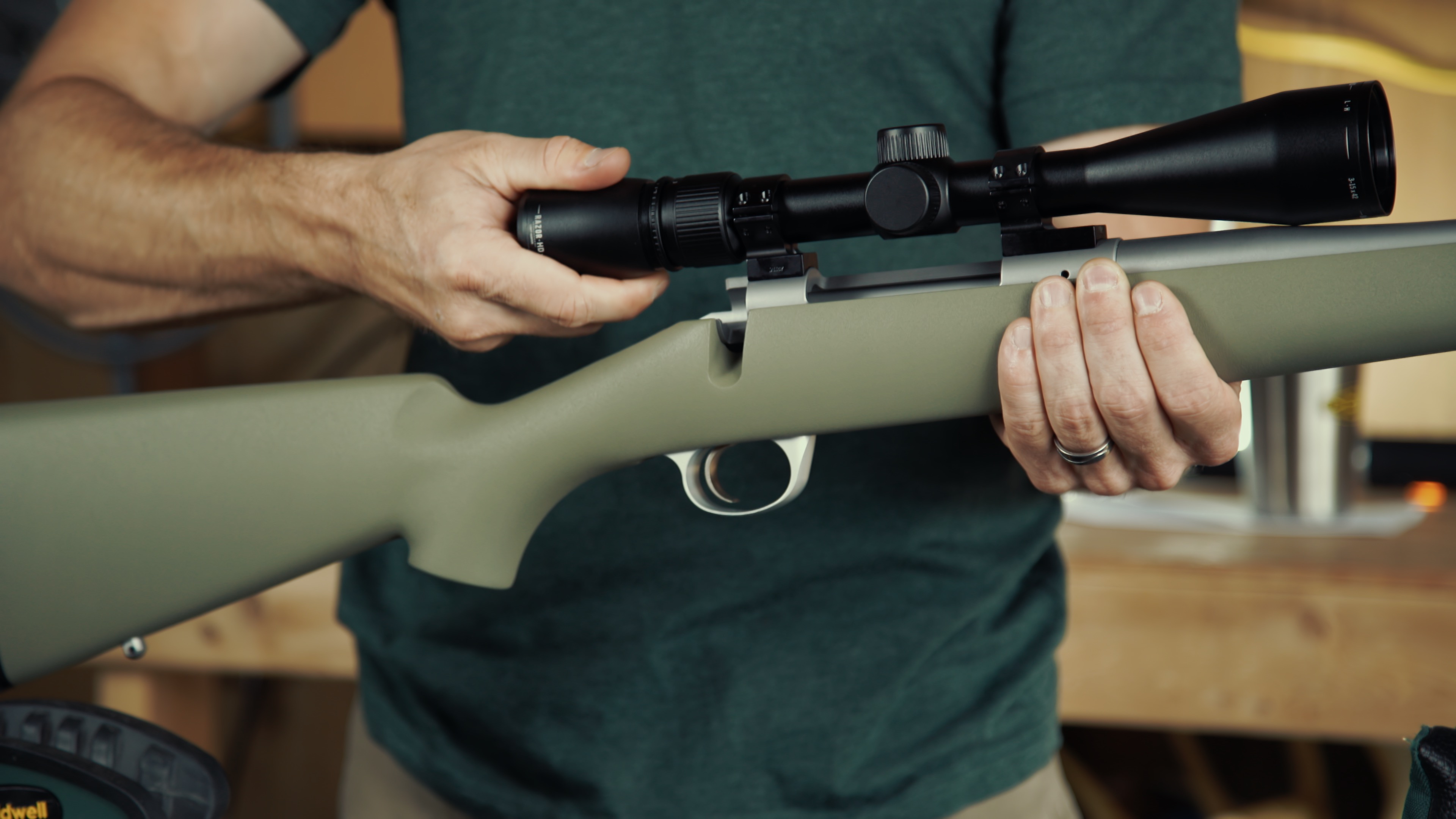 A shooter adjusting the ocular focus ring at the back of a rifle scope.