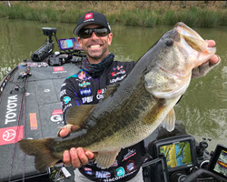 Professional angler Mike Iaconelli holding a large bass on a boat.