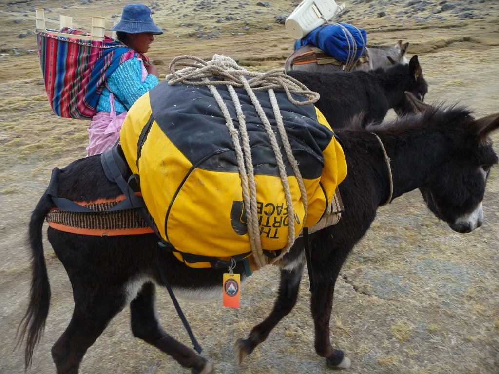 A red The North Face Base Camp duffel bag showing signs of heavy use on an expedition.