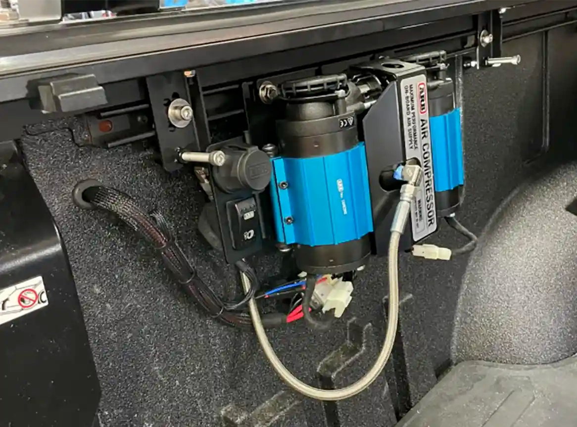 A high-performance portable air compressor installed inside an overland vehicle engine bay.