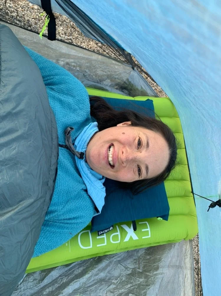 An backpacker sleeping on a blue Nemo Fillo pillow inside a tent in the backcountry.