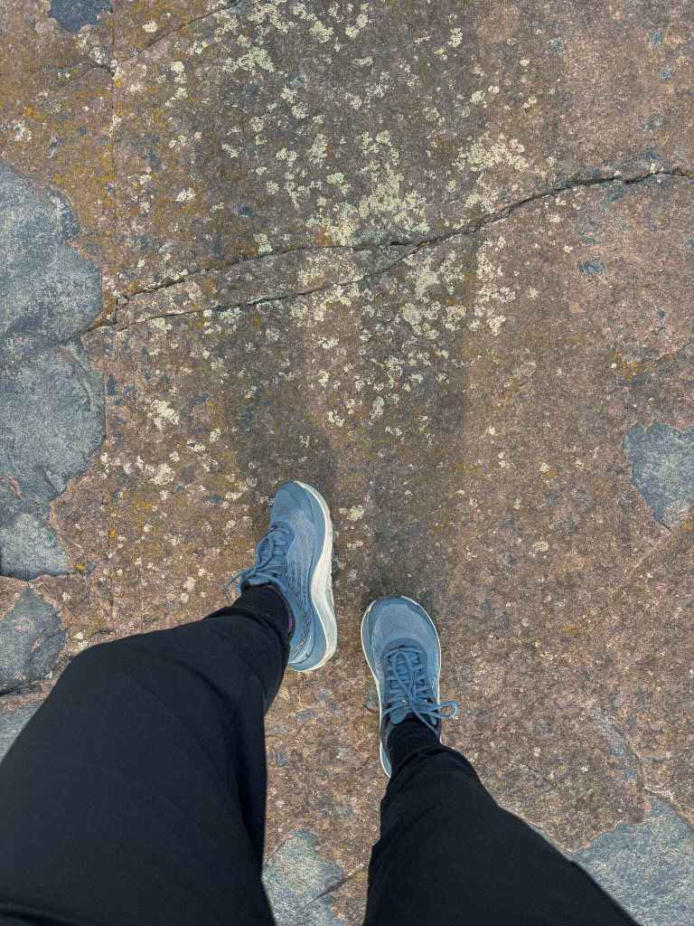 Close-up of Topo Athletic Ultraventure 4 trail-running shoes gripping a grey rock surface.