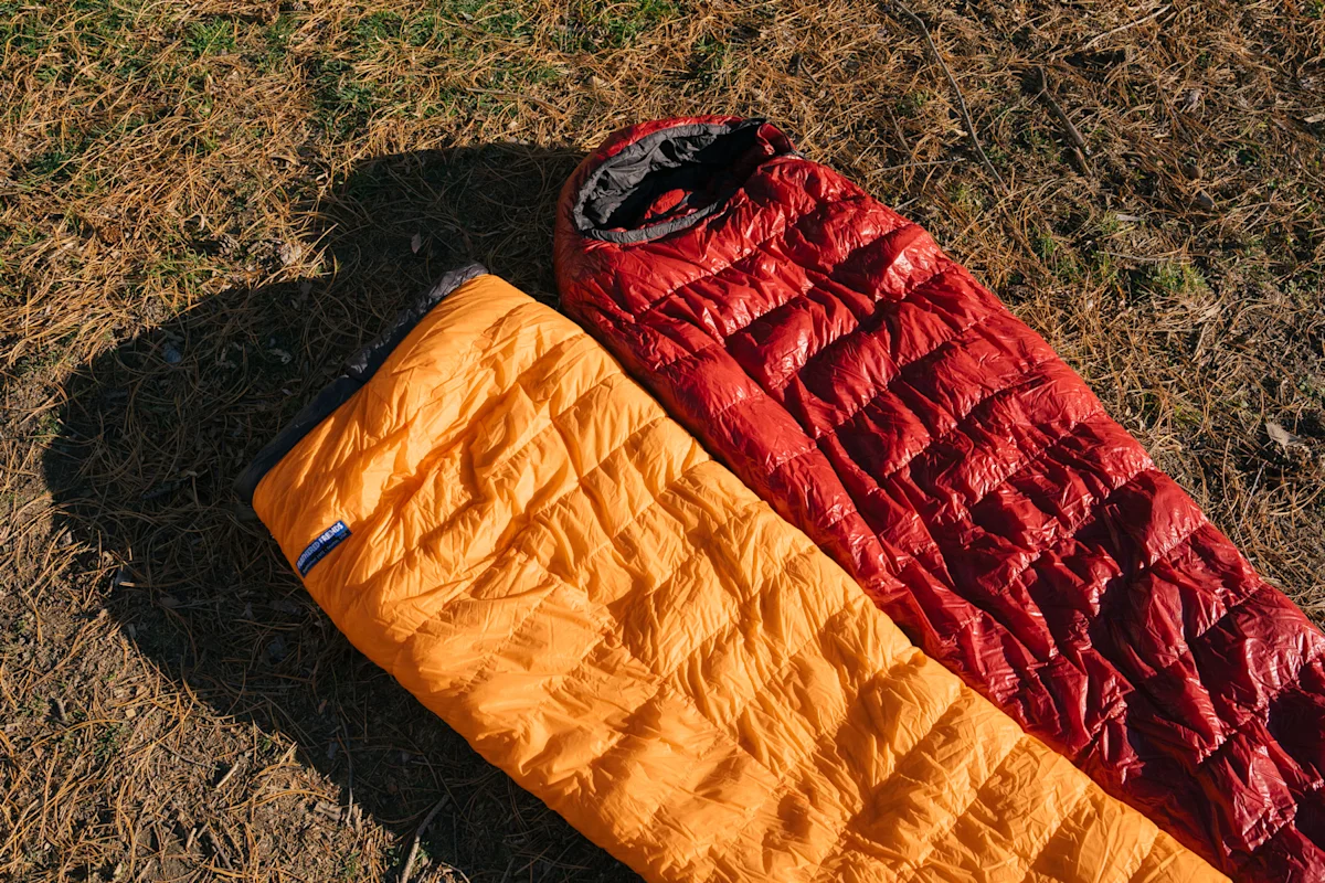 A visual comparison graphic showing a mummy sleeping bag alongside an ultralight backpacking quilt.