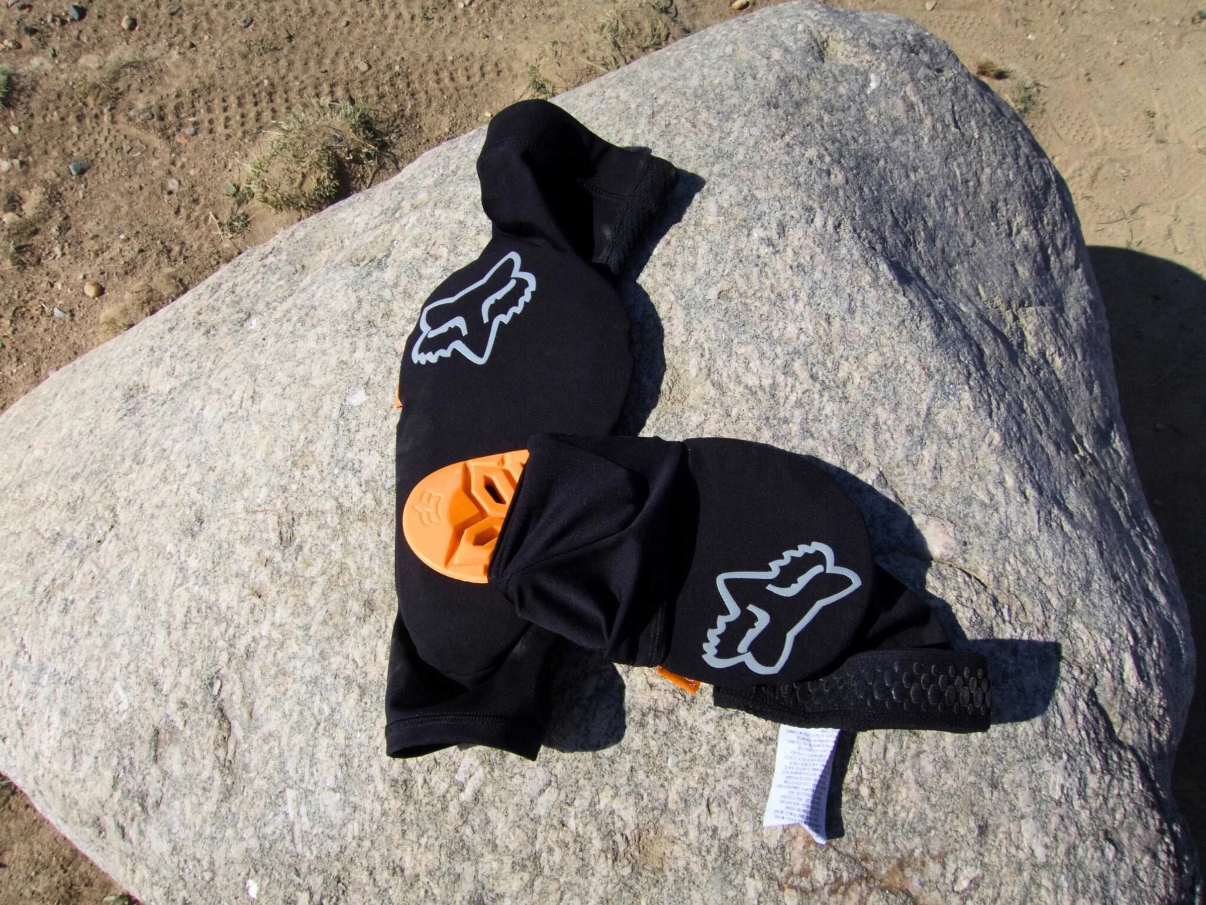 A hand removing a yellow D3O insert from a Fox Enduro elbow pad sleeve.