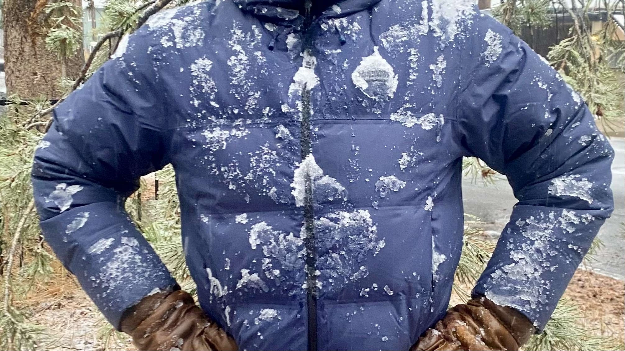 A close-up of a person wearing a Patagonia Jackson Glacier jacket covered in wet, heavy snow.
