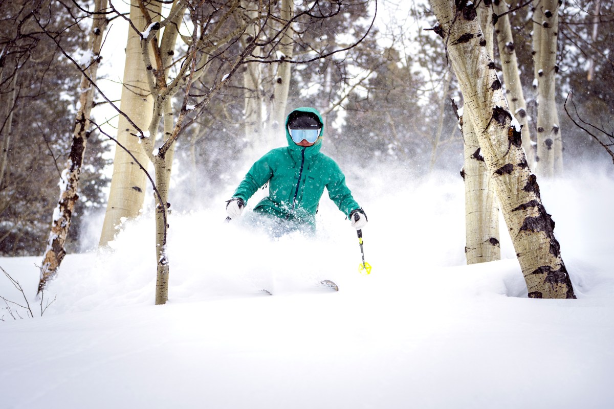 Expert gear testers evaluating multiple ski jackets in a snowy high-elevation environment.