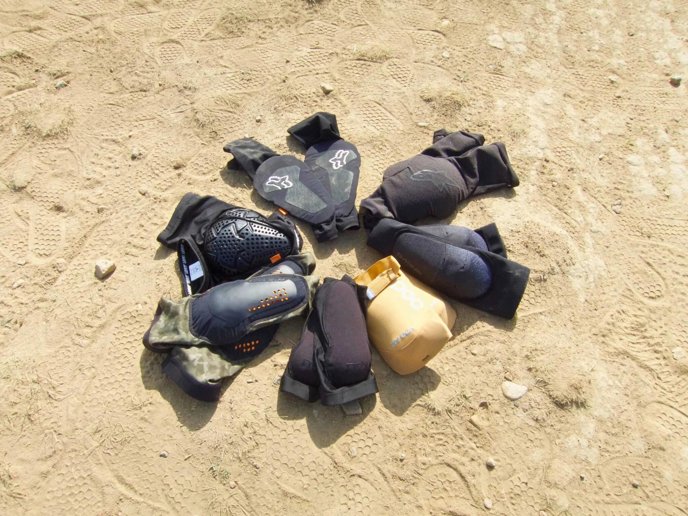 A collection of various mountain bike elbow pads laid out on a table for Comparison.