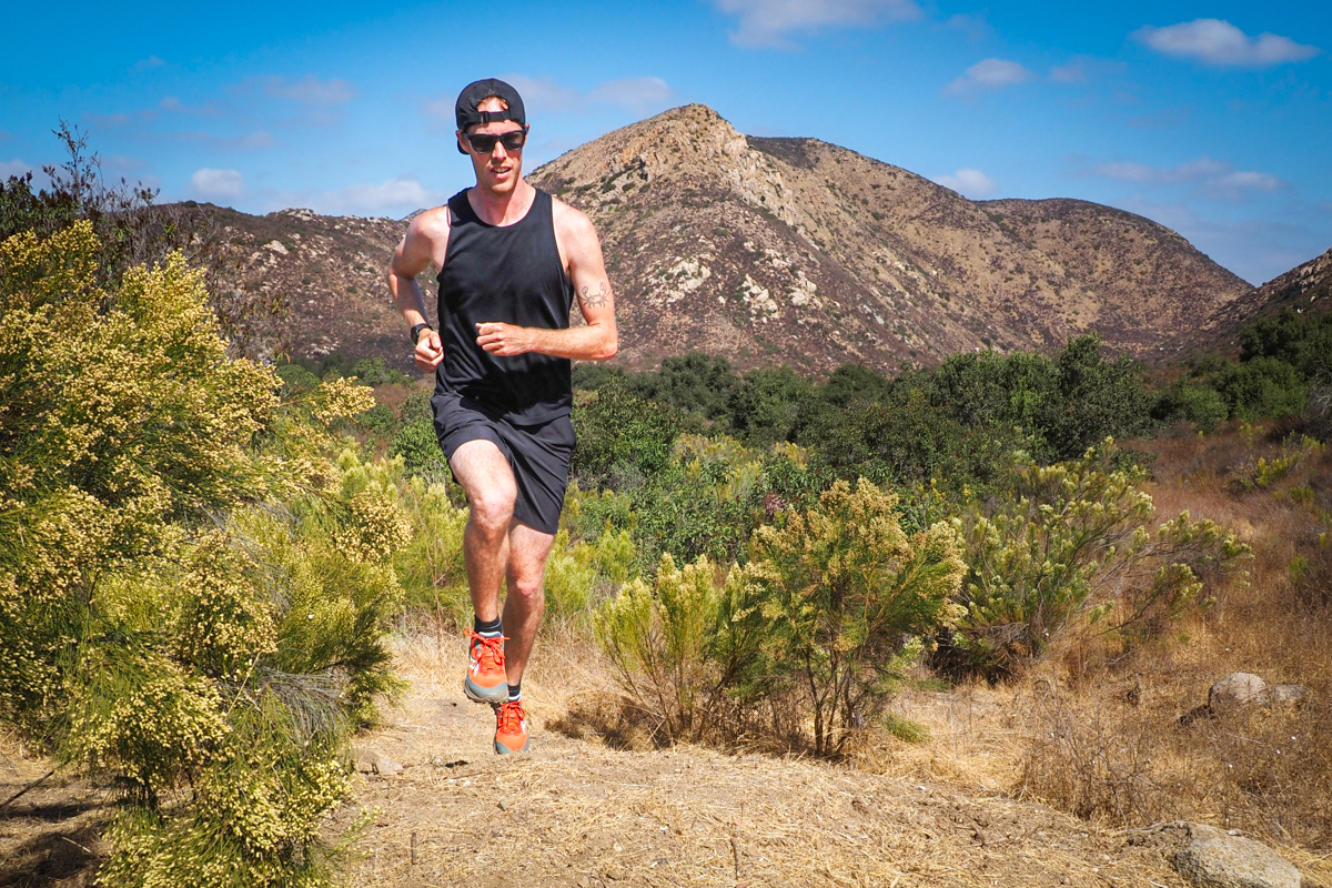A man running on a desert trail wearing Saucony Peregrine 15 trail shoes.