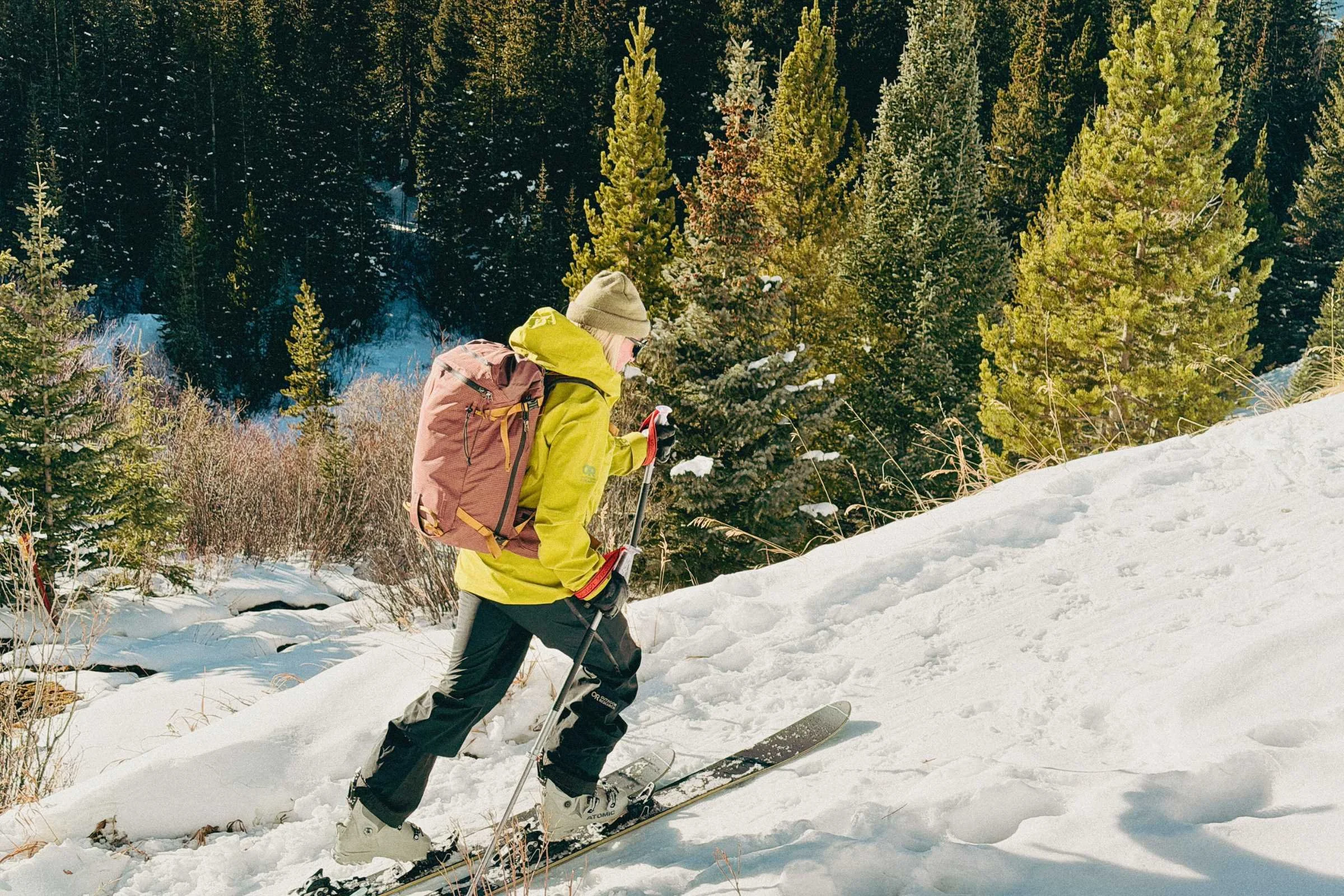 A female backcountry skier skinning uphill in a light purple Outdoor Research Cloudchaser shell.