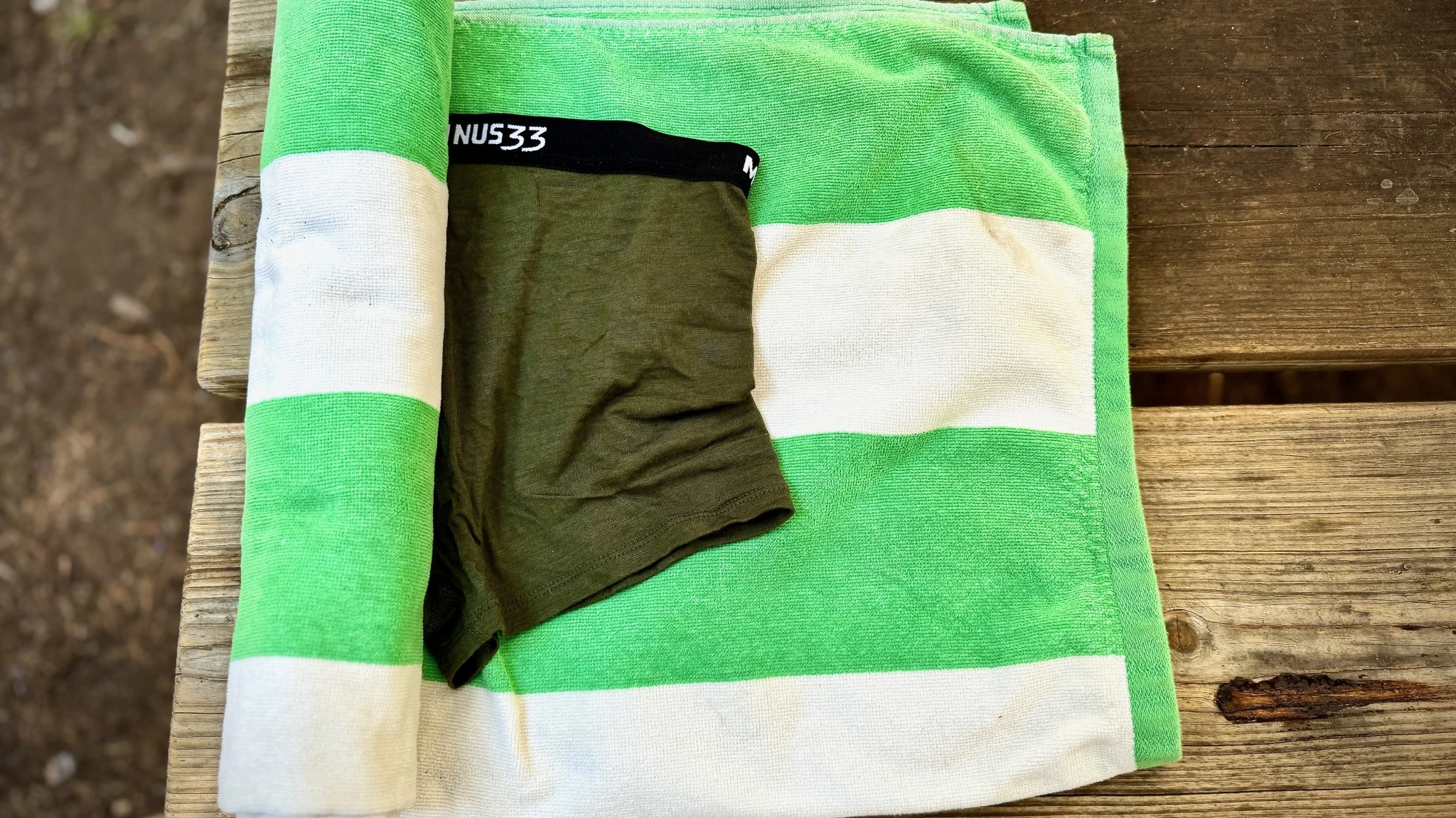 A pair of boy shorts being rolled up inside a white towel for quicker drying.